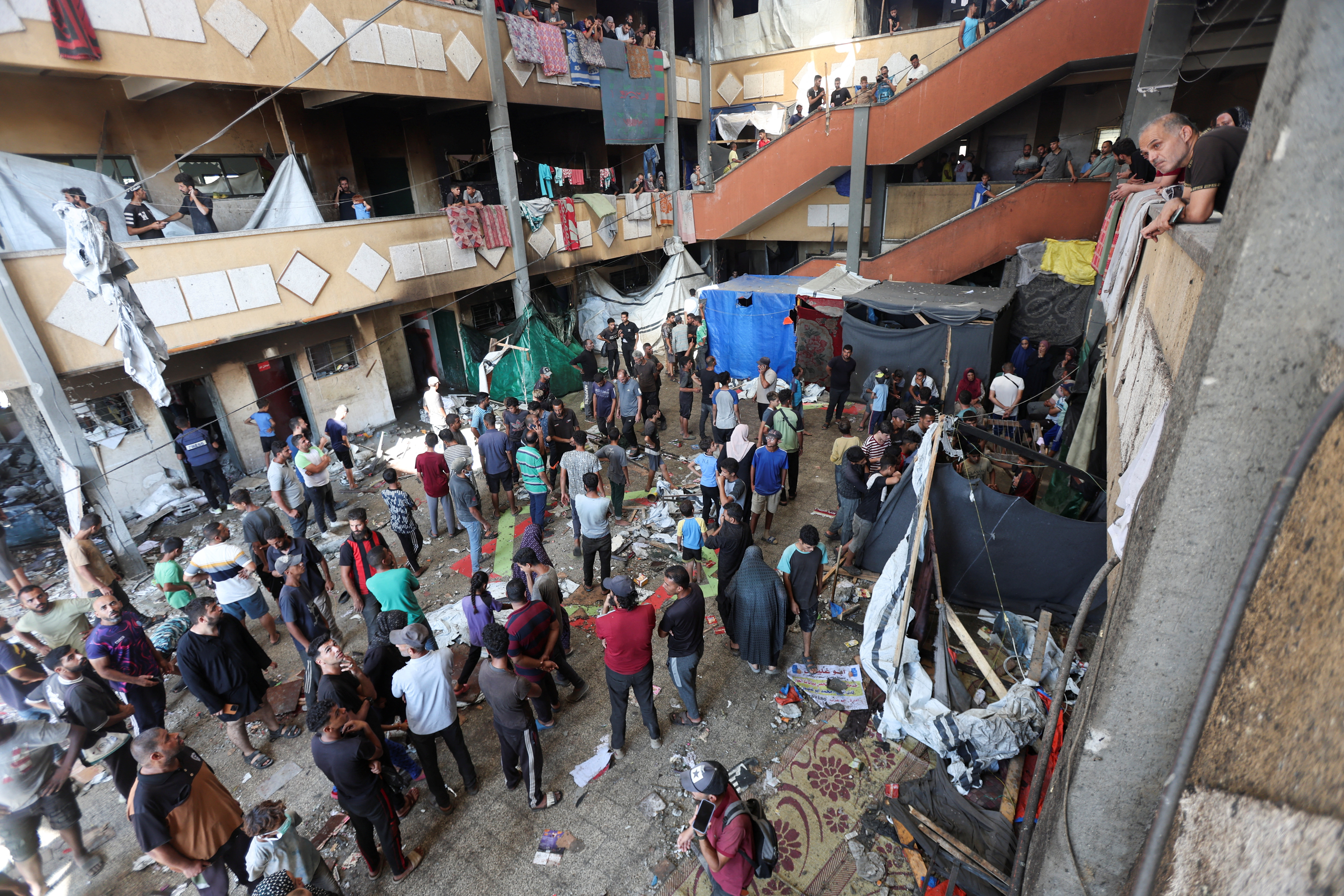Palestinians inspect the site of an Israeli strike on a school sheltering displaced people