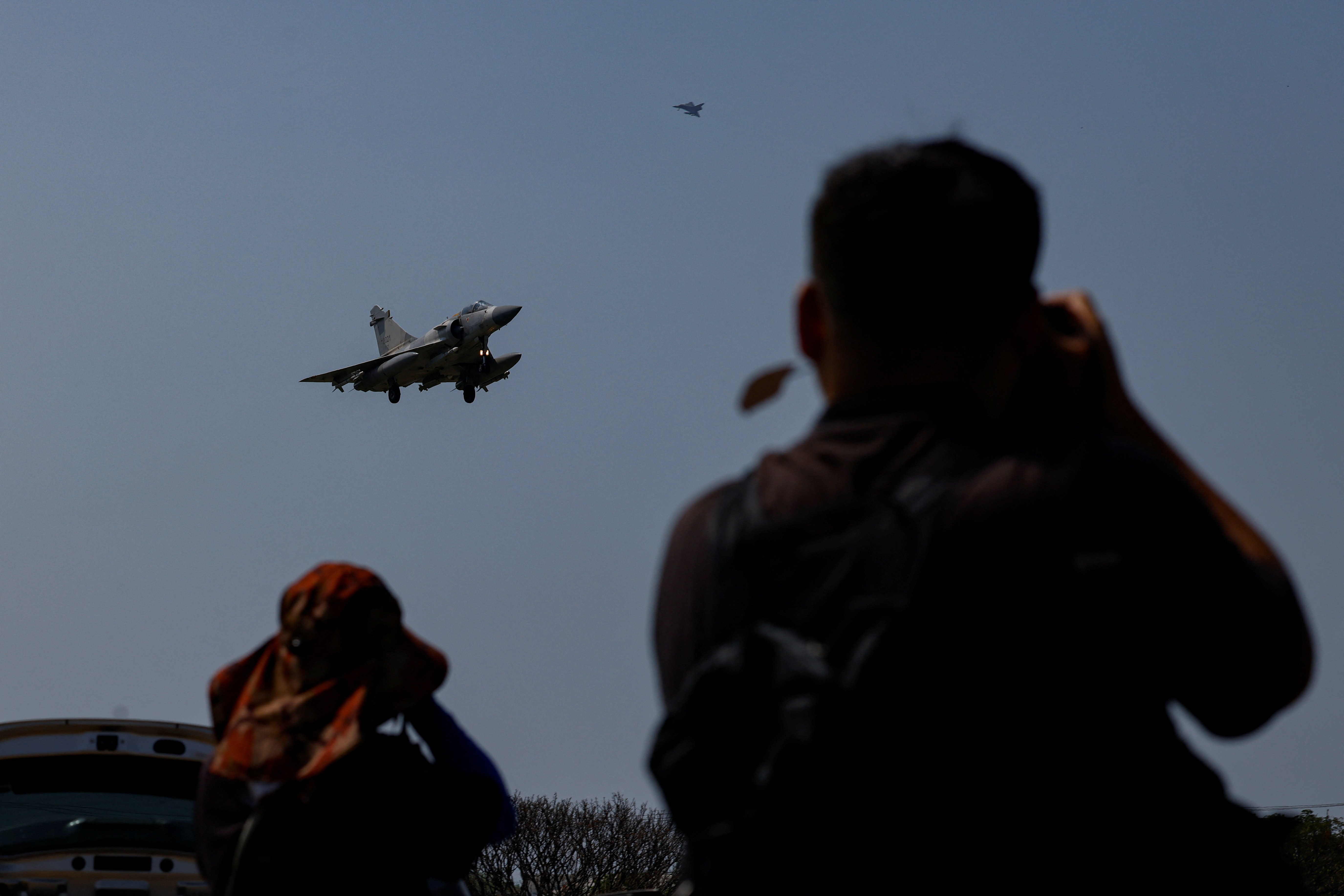Taiwan Air Force Mirage fighters preparing to land at Hsinchi airbase. Two people arew watching the sky