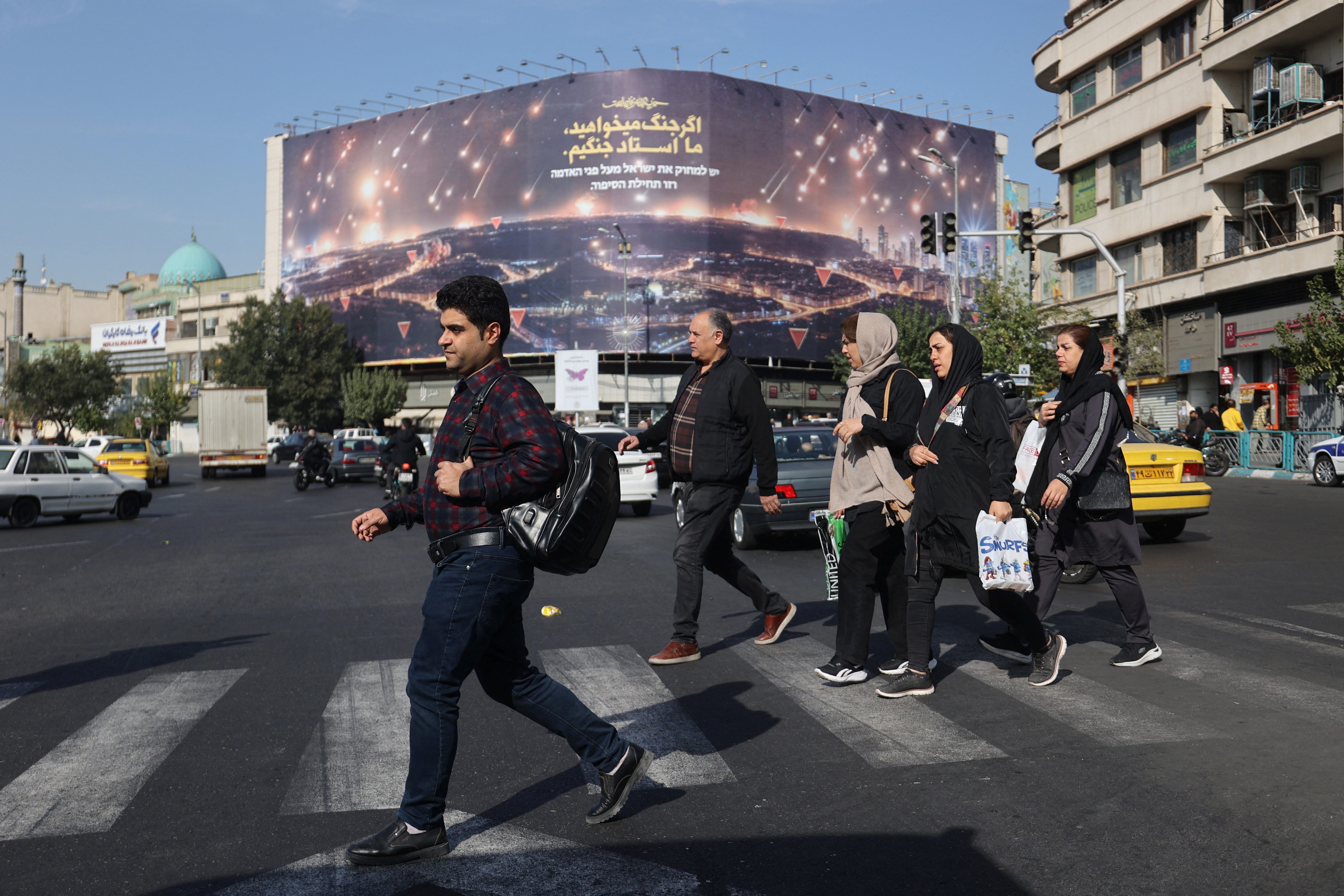 Iranians walk next to an anti-Israel billboard on a street after several explosions were heard, in Tehran, Iran, October 26, 2024.