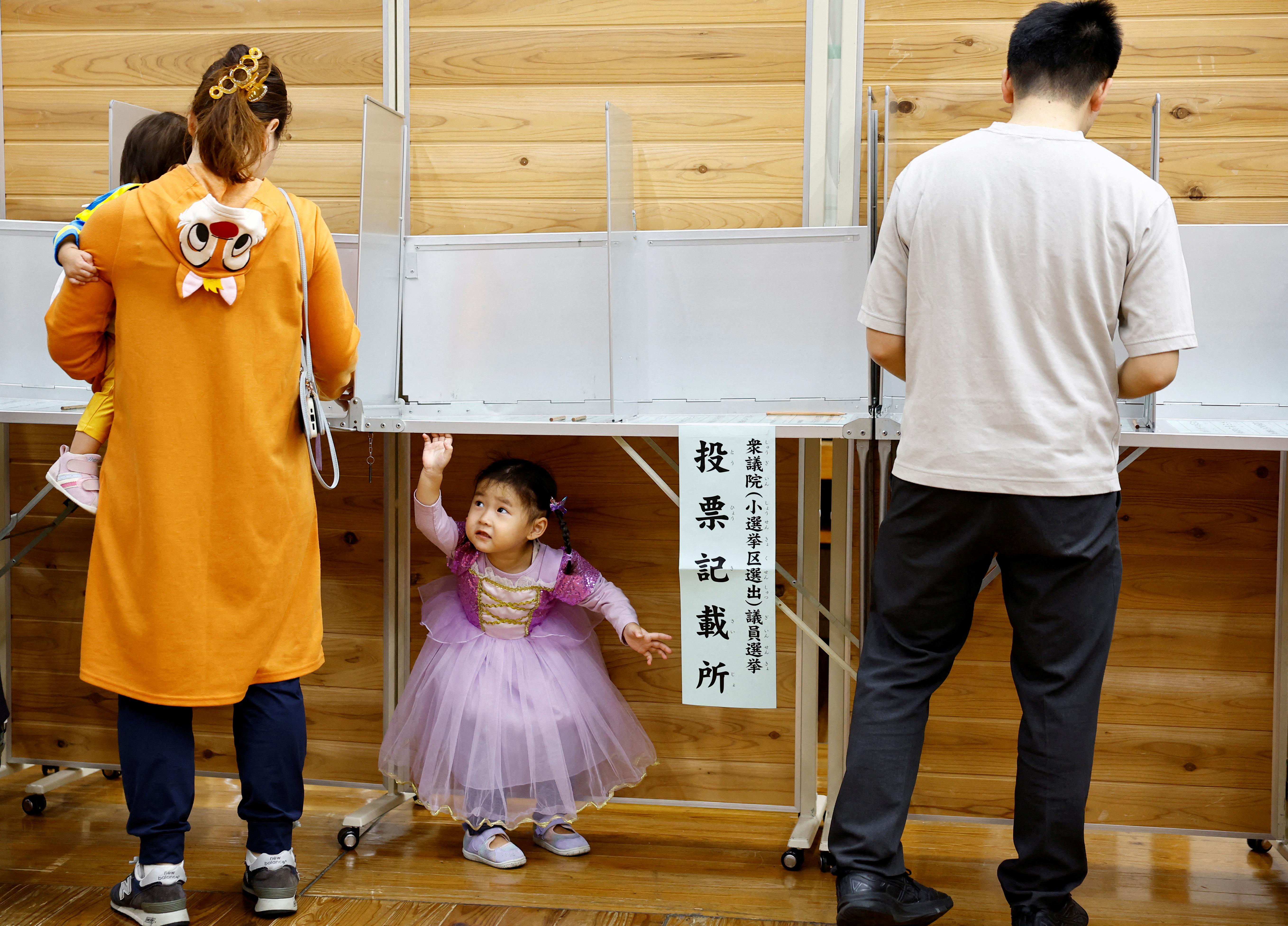 A woman accompanying her children in Halloween costume prepares to vote