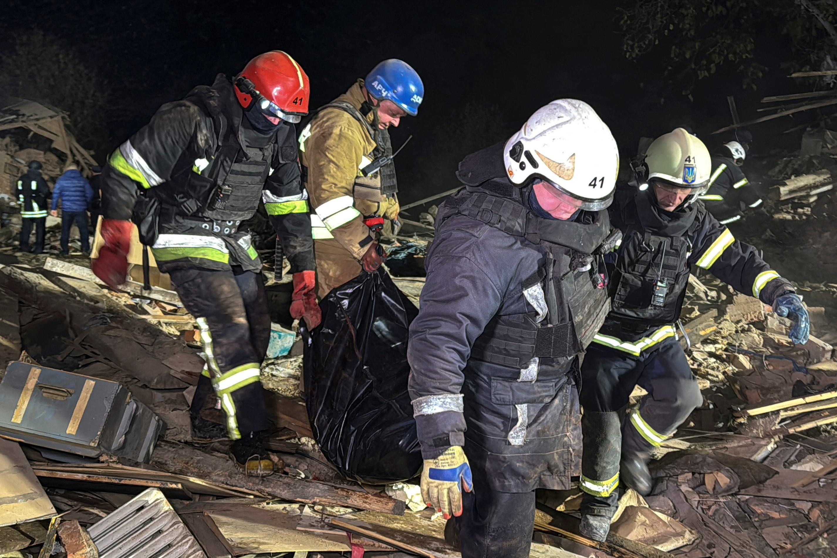 Rescuers carry the body of a person found under debris of a private house which was hit by a Russian missile strike in Kharkiv