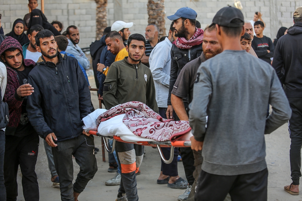 men carry a stretcher with a body wrapped in a red and white blanket