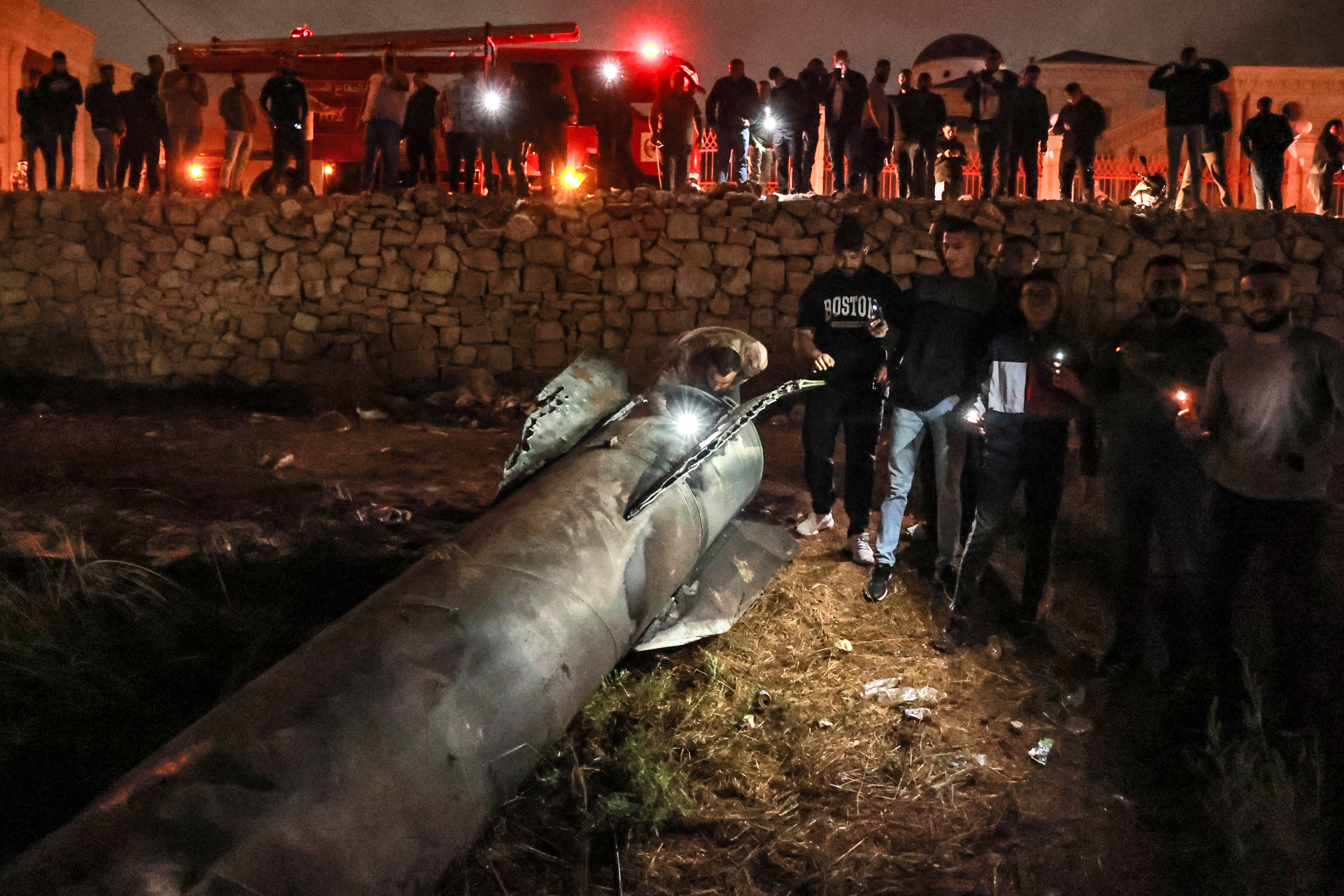 Palestinian youths inspect a fallen projectile after Iran launched a barrage of missiles at Israel in response to the killings of Lebanese Hezbollah leader Nasrallah and other Iran-backed militants, in Ramallah in the occupied West Bank on October 1, 2024. - Reports said Iran fired between 150 and 200 missiles in the attack, the country's second on Israel after a missile and drone attack in April in response to a deadly Israeli air strike on the Iranian consulate in Damascus. (Photo by Zain JAAFAR / AFP)