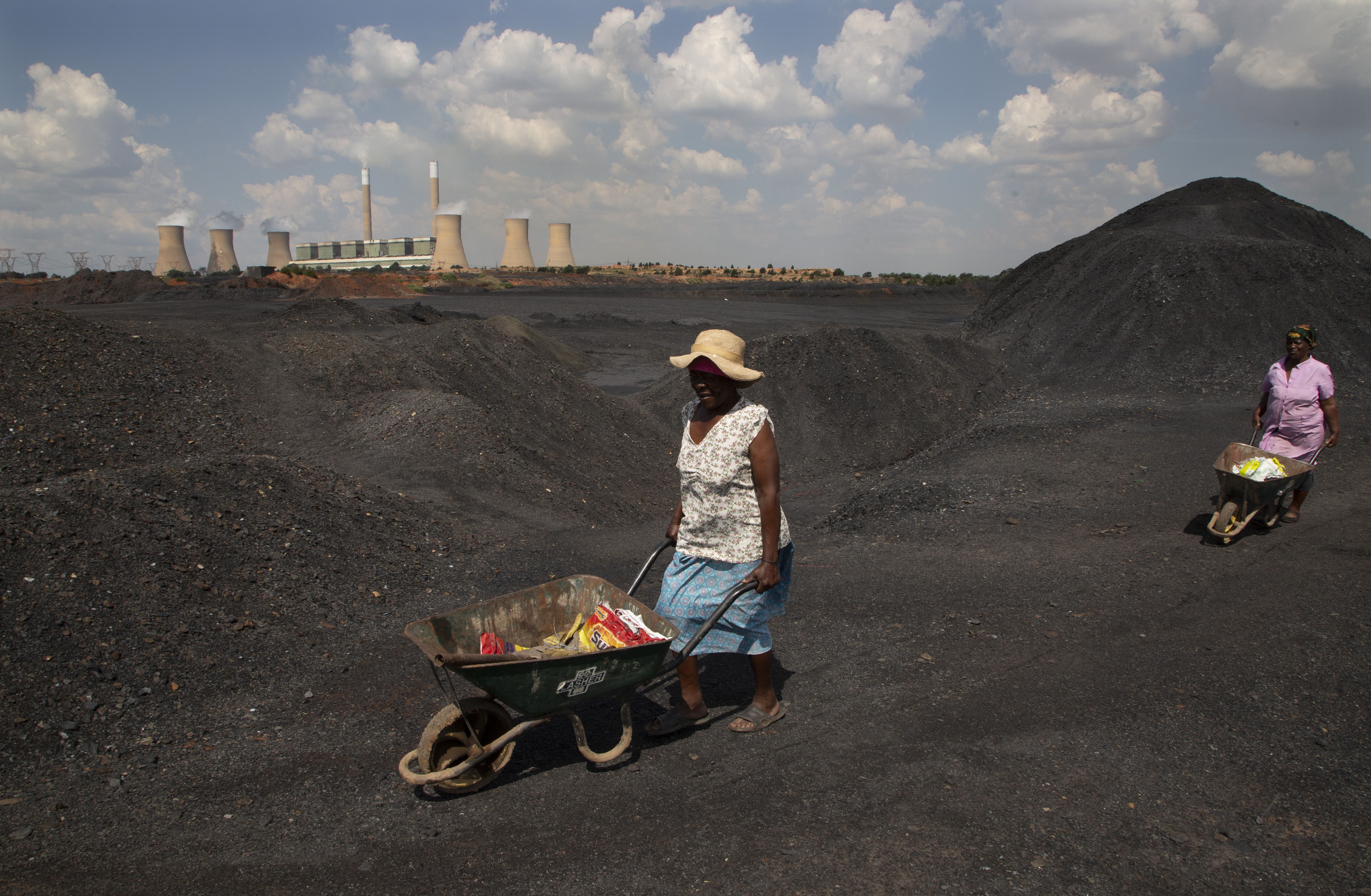 A woman pushes a wheel barrow in a coal mine dump on an afternoon in a power station in Johannesburg