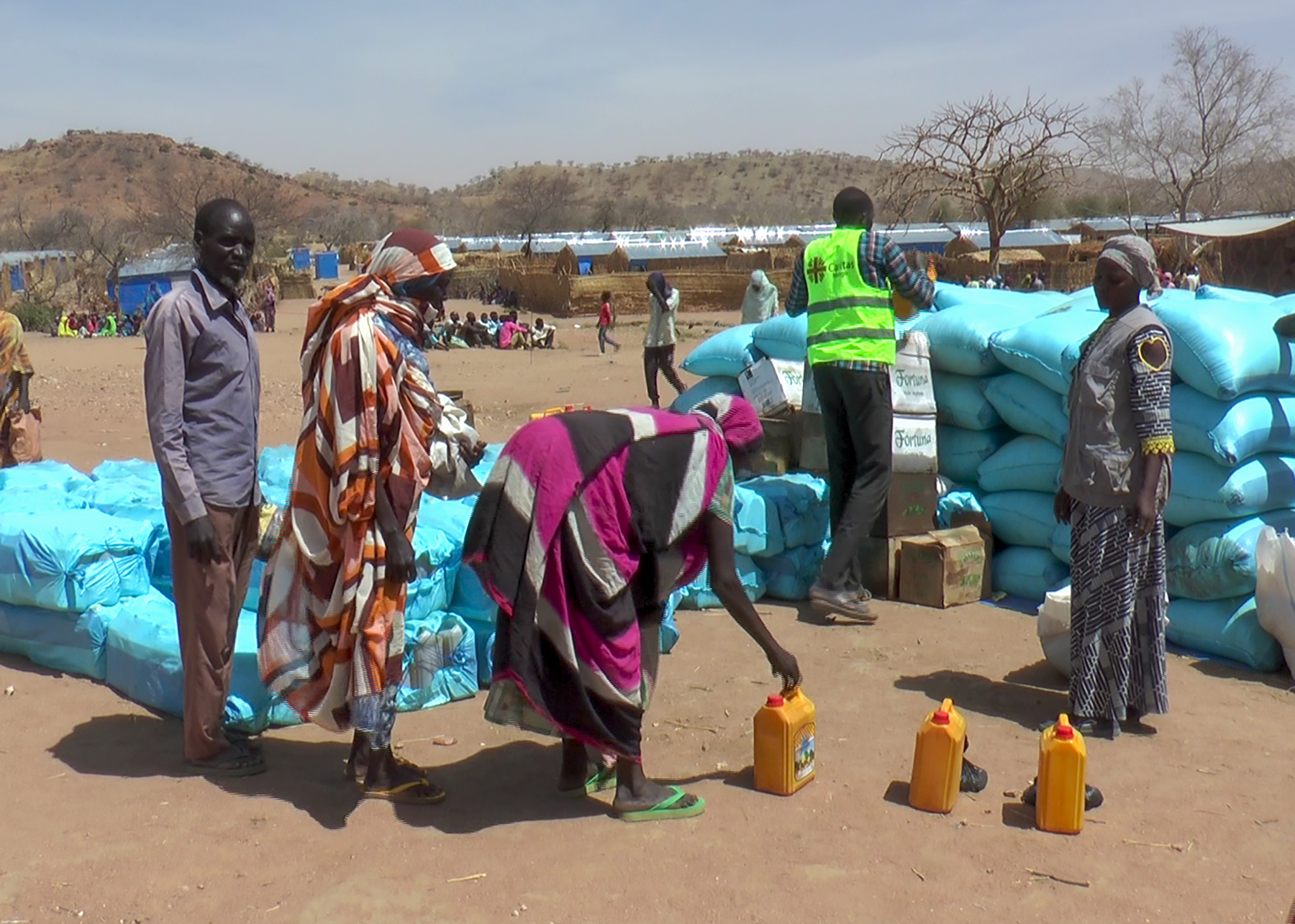 Sudanese refugees stand around food aid in Metche camp, Chad