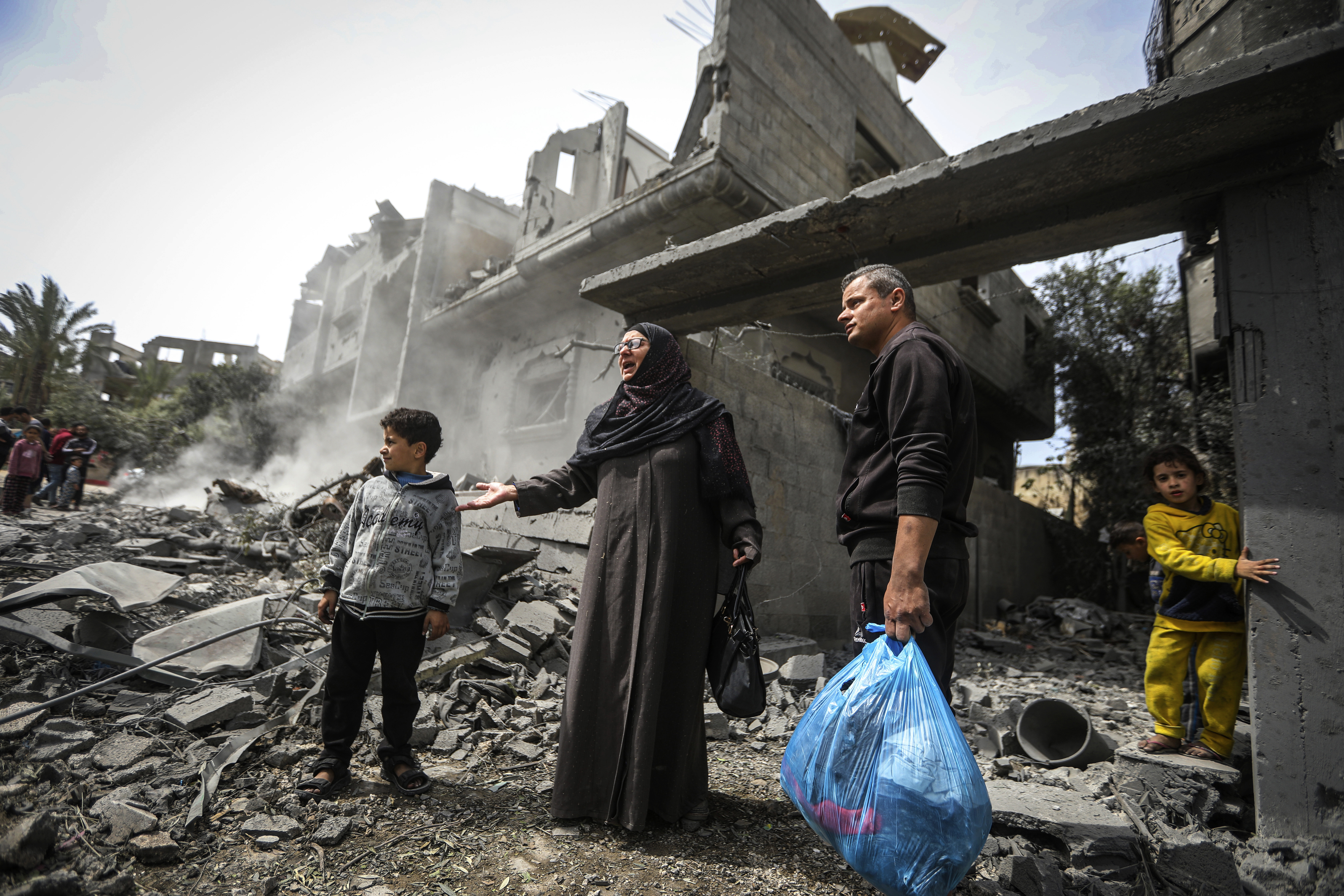 Palestinians collect their belongings from the rubble of a residential building for the Moussa family after an Israeli airstrike in the Maghazi refugee camp
