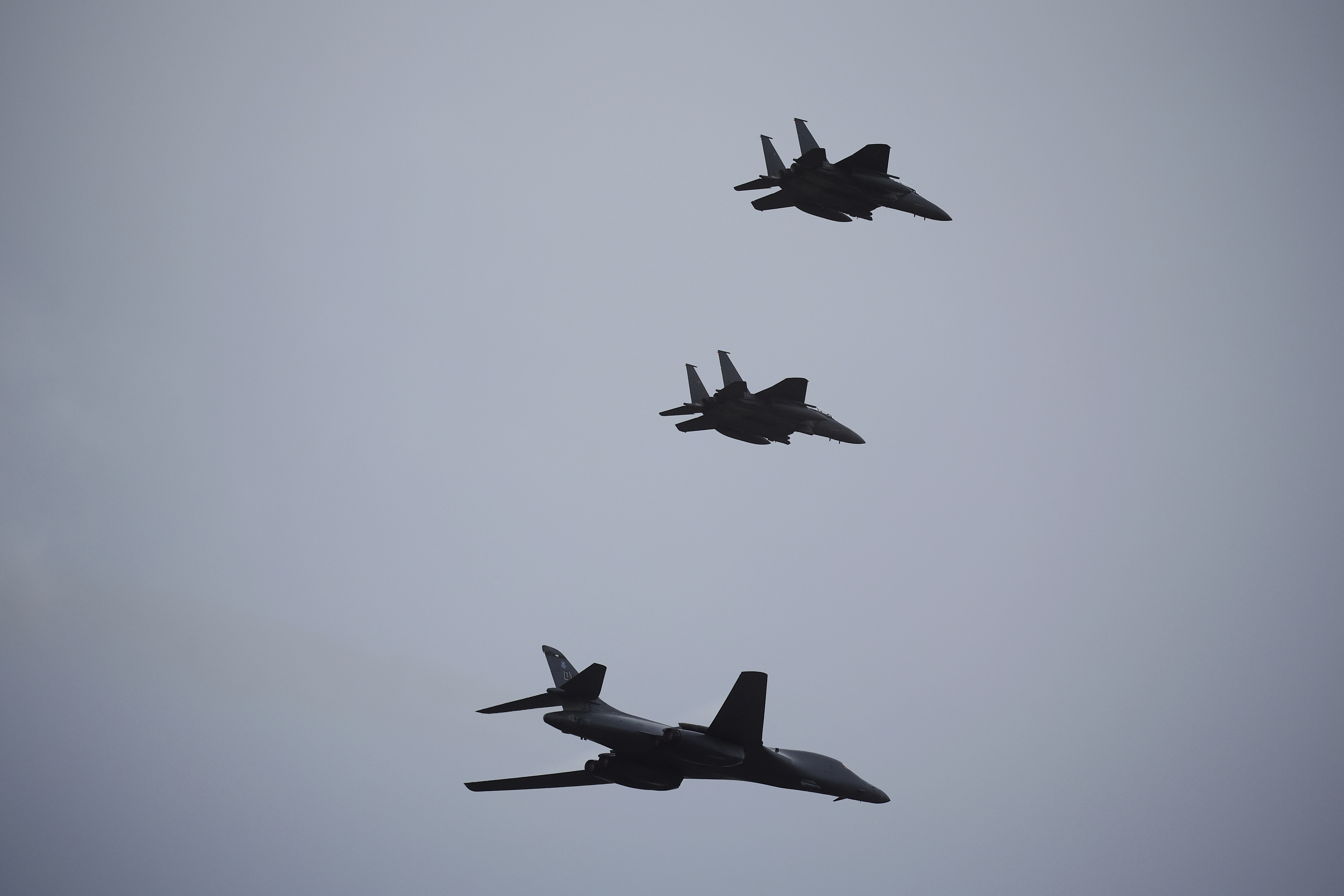 A US Air Force B1 Bomber with two South Korean fighter jets in the air above the Seongnam base