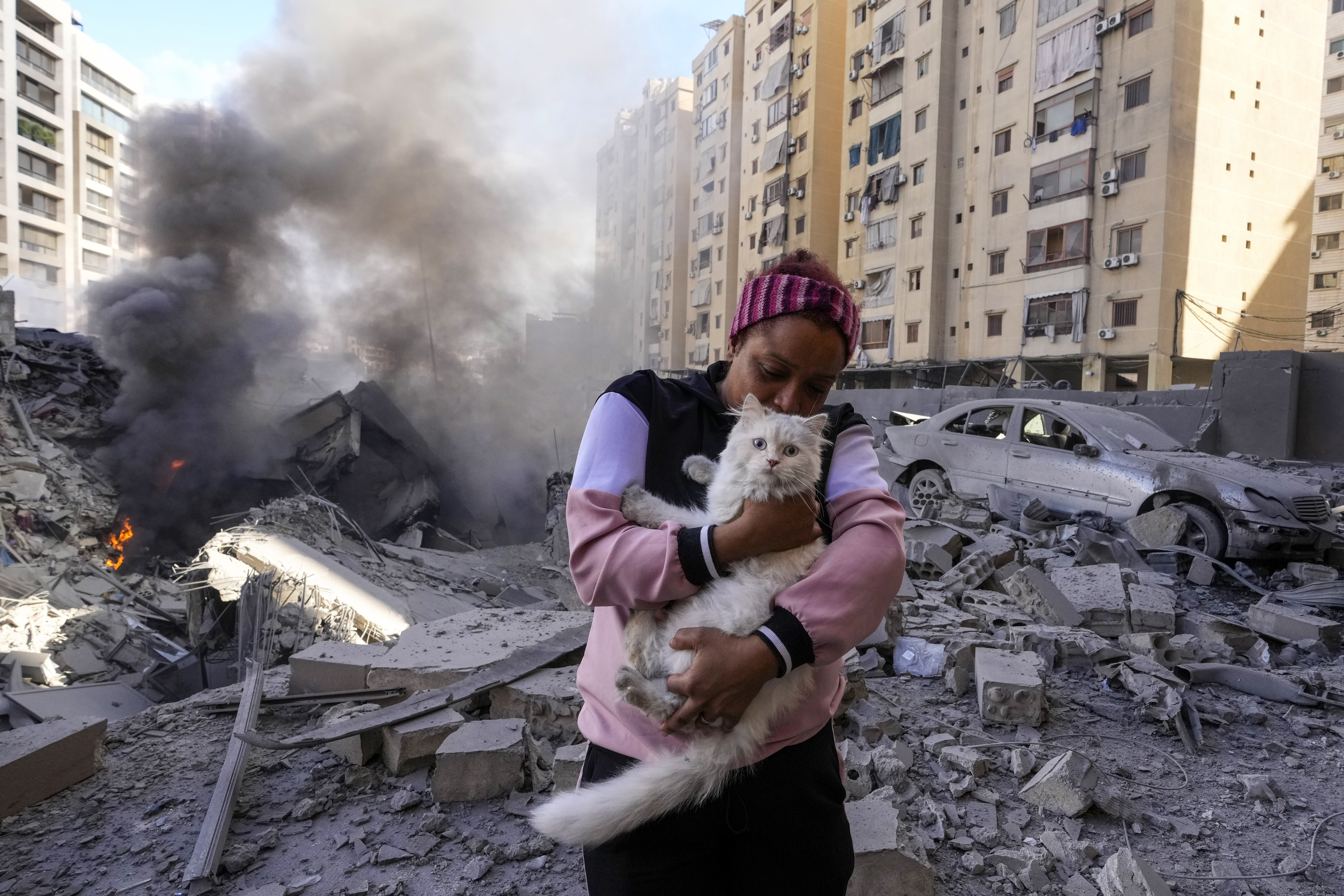 A woman holds her cat in front of a destroyed building at the site of an Israeli airstrike in Dahiyeh, Beirut, Lebanon, Wednesday
