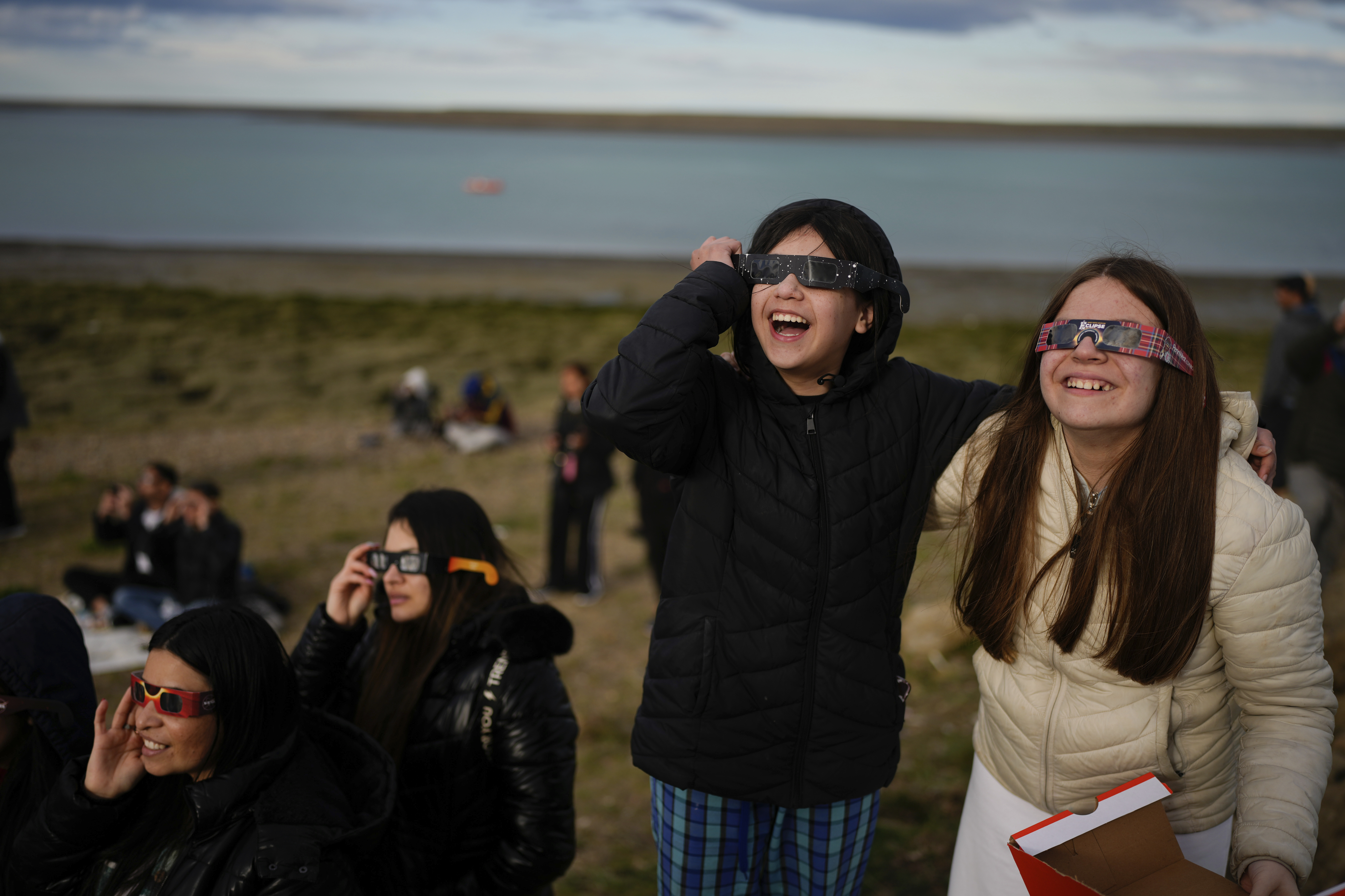 People watch the eclipse through protective glasses.