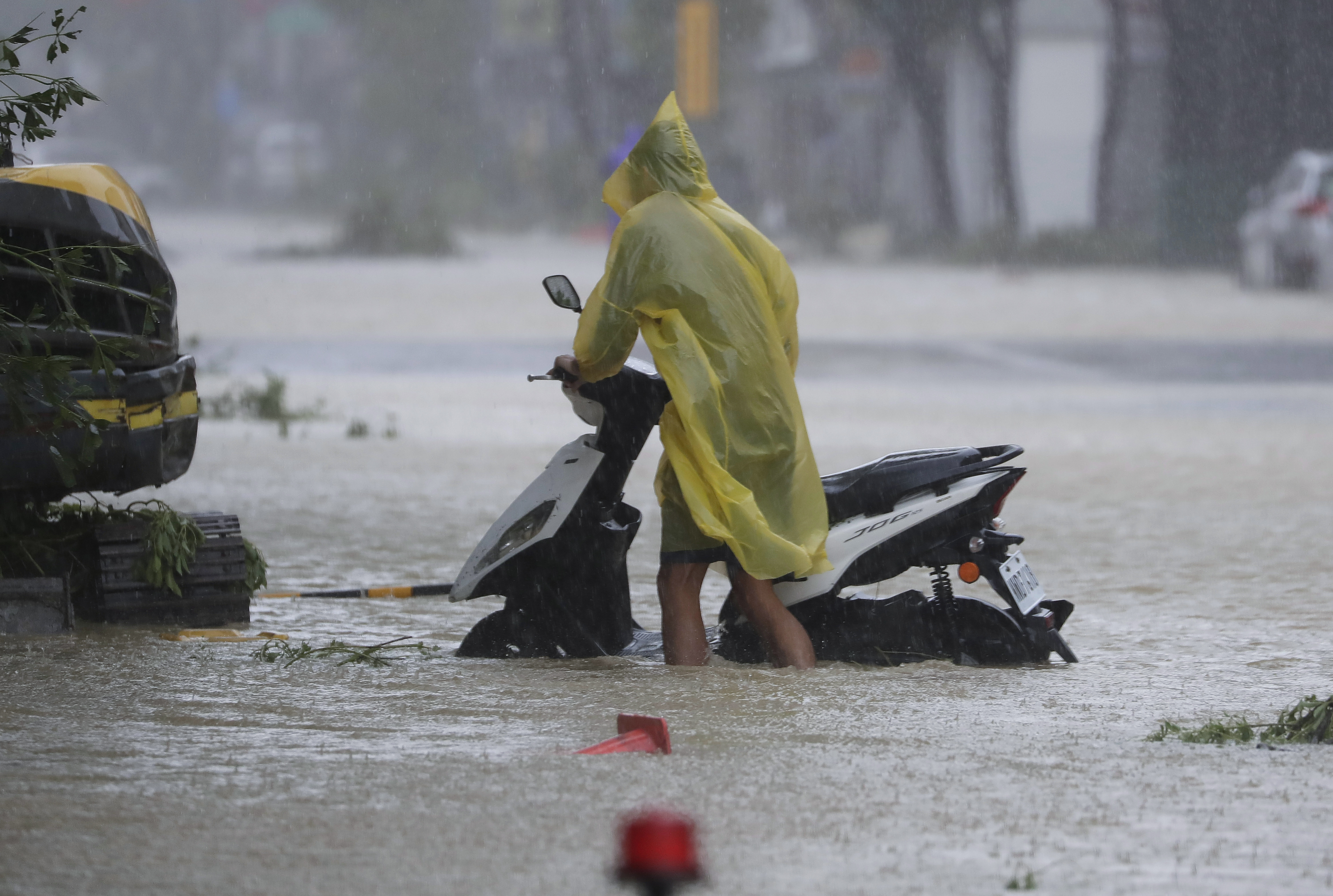 A man pushes a motorbike through a flooded road as Typhoon Krathon makes landfall in Kaohsiung, southern Taiwan, Thursday