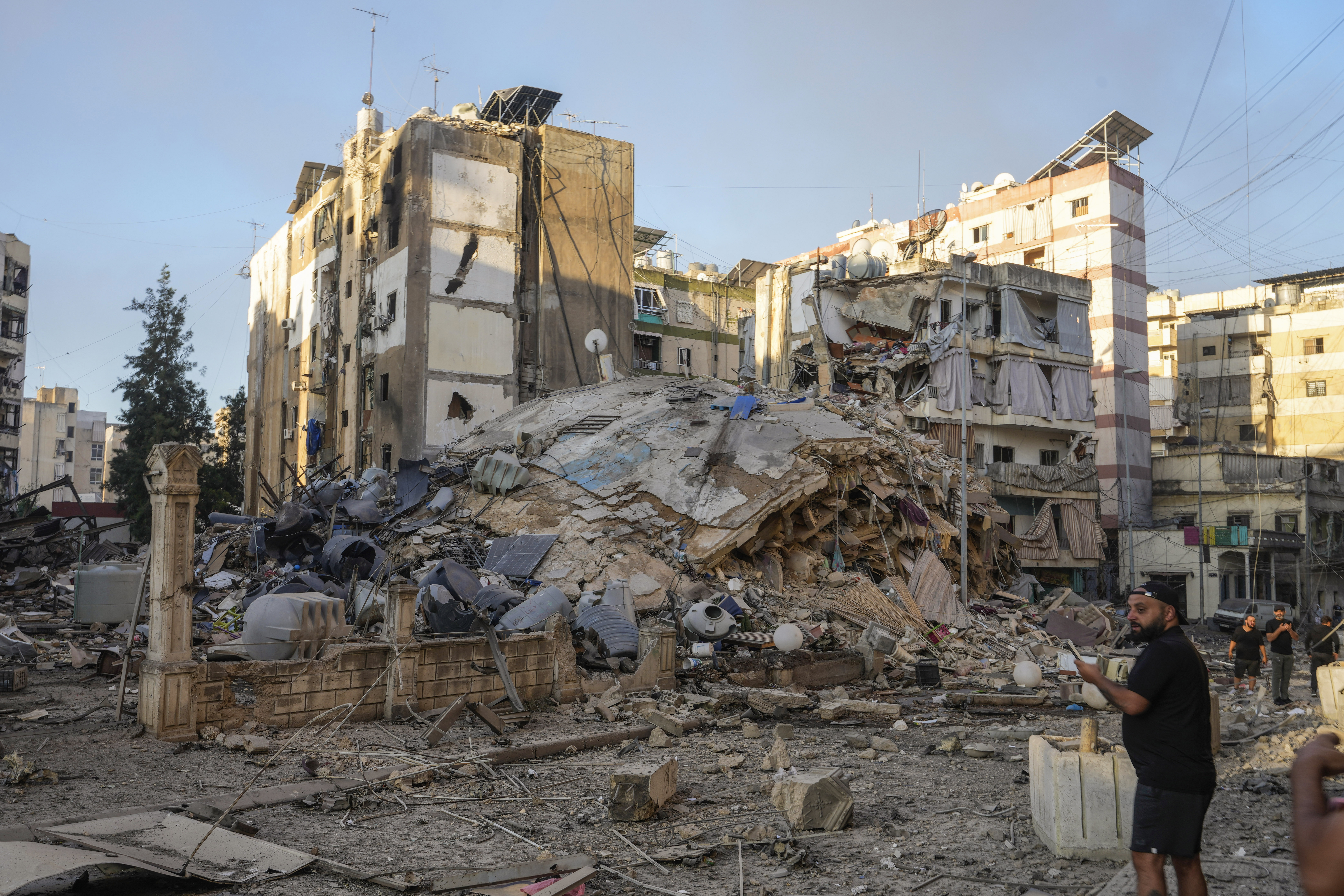 A man documents the damaged buildings at the site of an Israeli airstrike in Dahiyeh, Beirut, Lebanon, Friday, Oct. 4