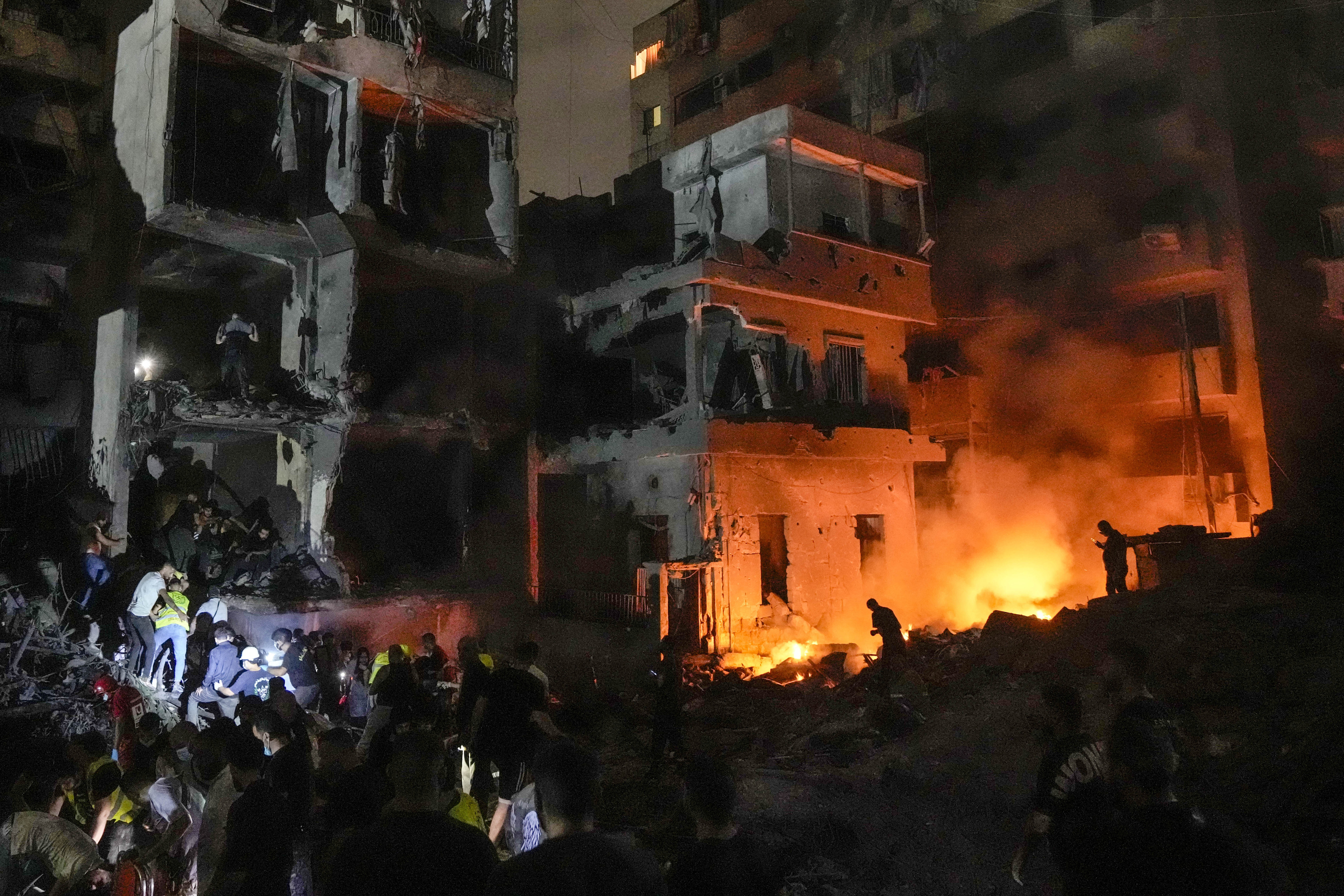 People gather in front of destroyed buildings hit by an Israeli airstrike in central Beirut, Lebanon, Thursday, Oct. 10