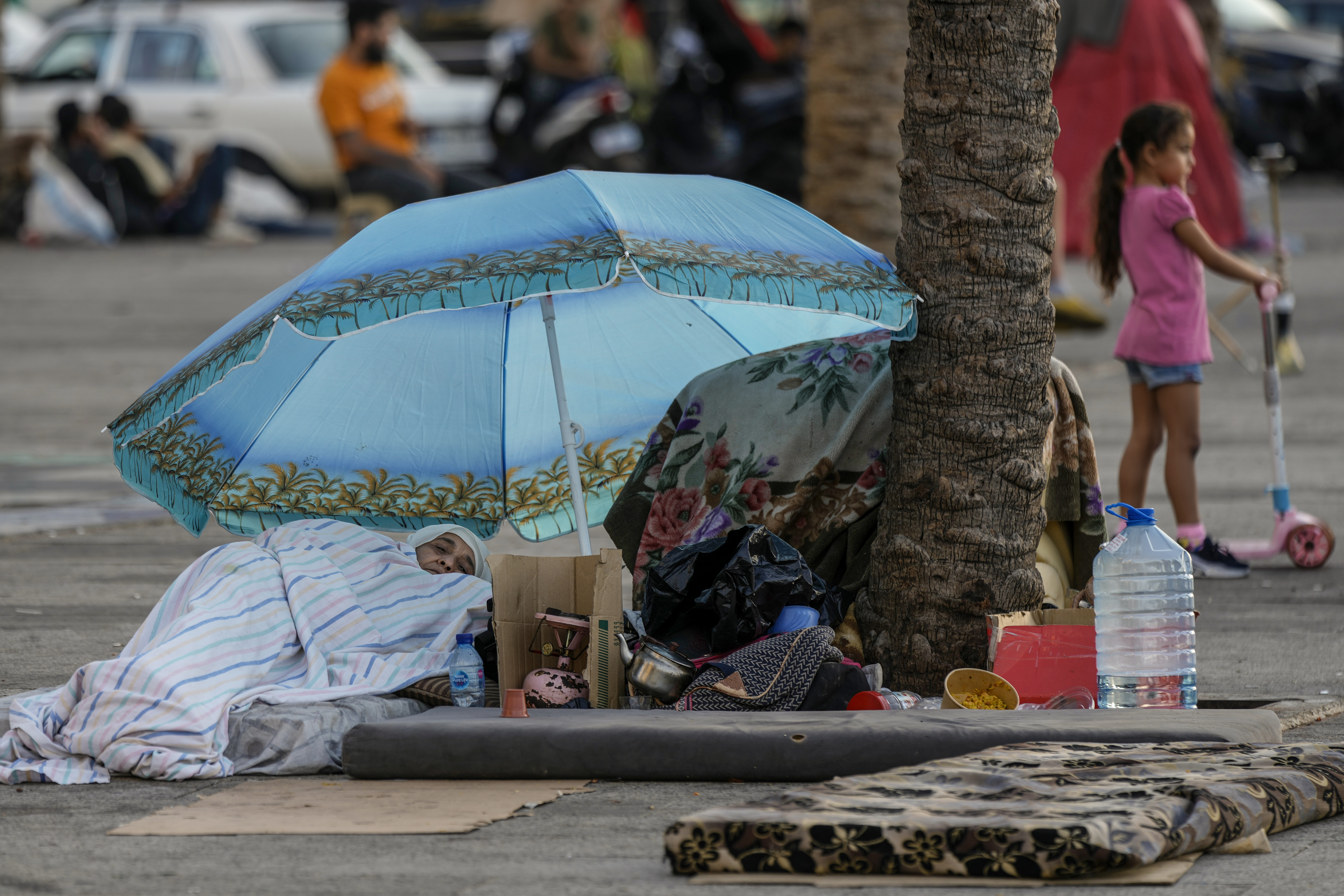 A woman sleeps on Beirut's corniche after fleeing the Israeli airstrikes in Dahiyeh, Lebanon, Monday, Oct. 14