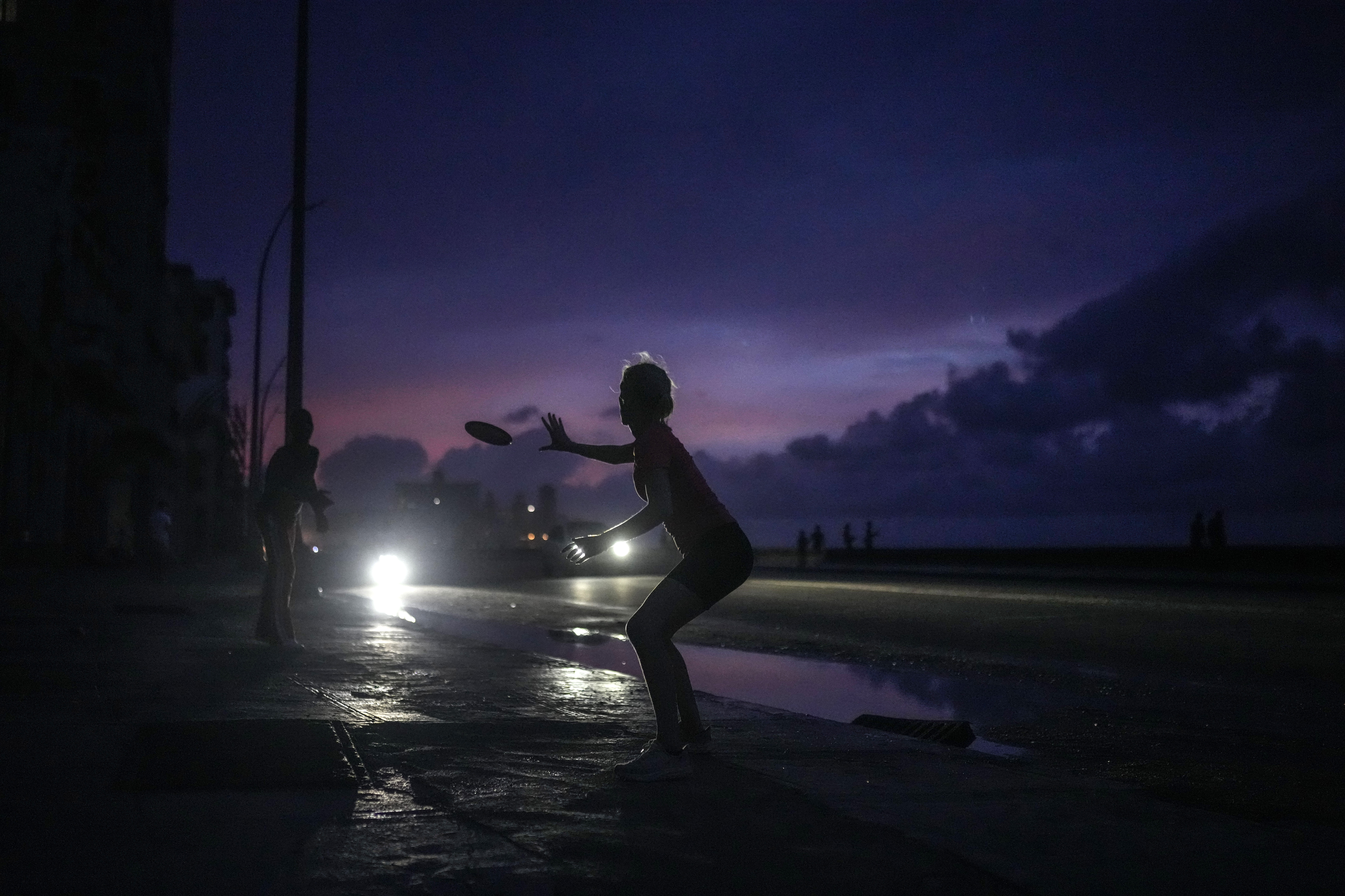 A woman plays frisbee at night during a blackout in Havana.