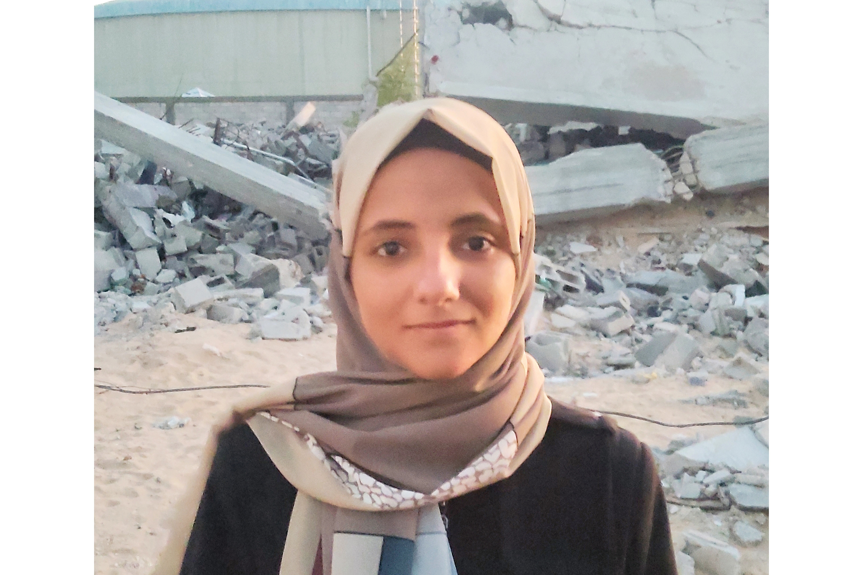 A young woman posing for a photo to the background of rubble