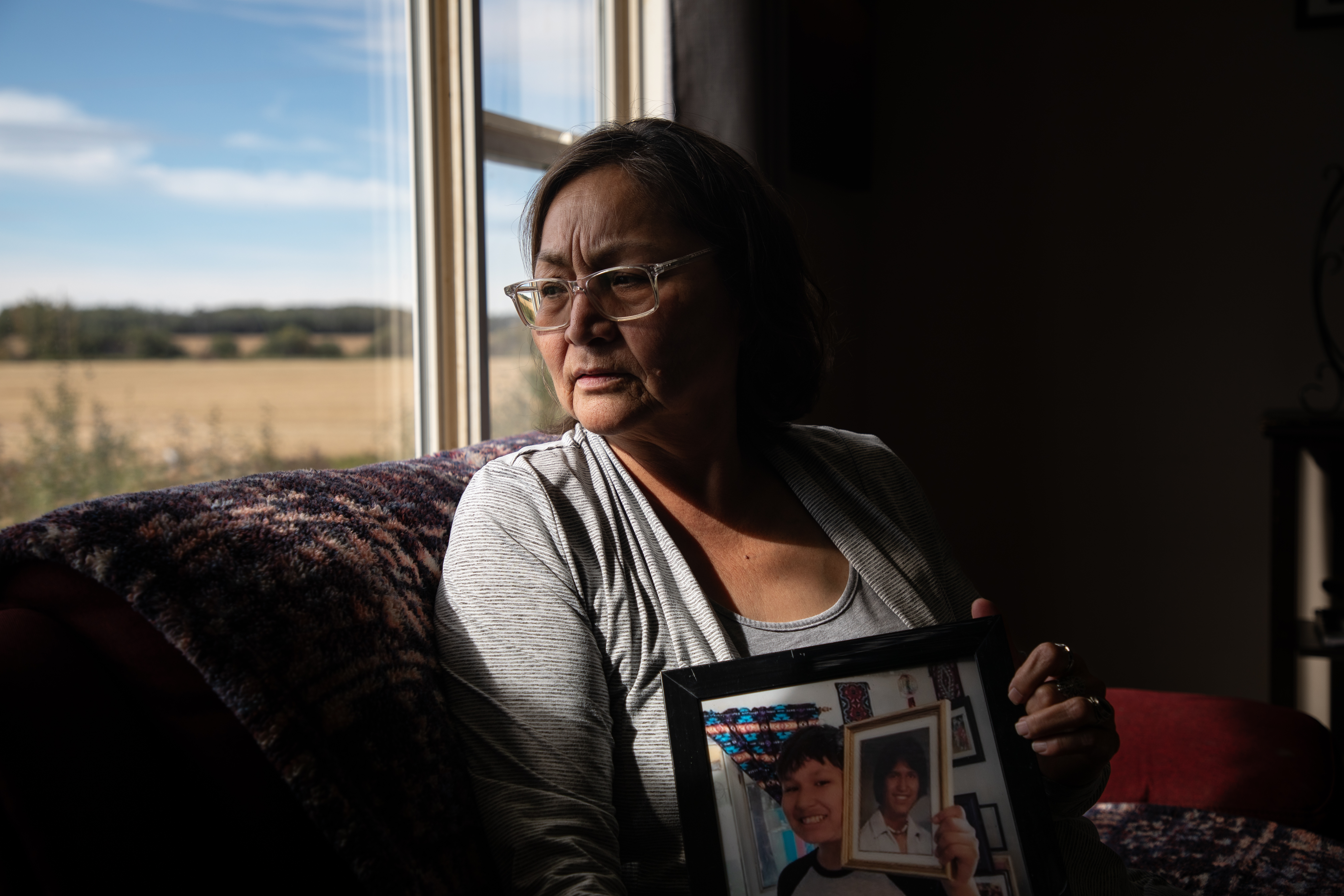 Nadalie Lightning stares out of window as she holds photos of her grandson