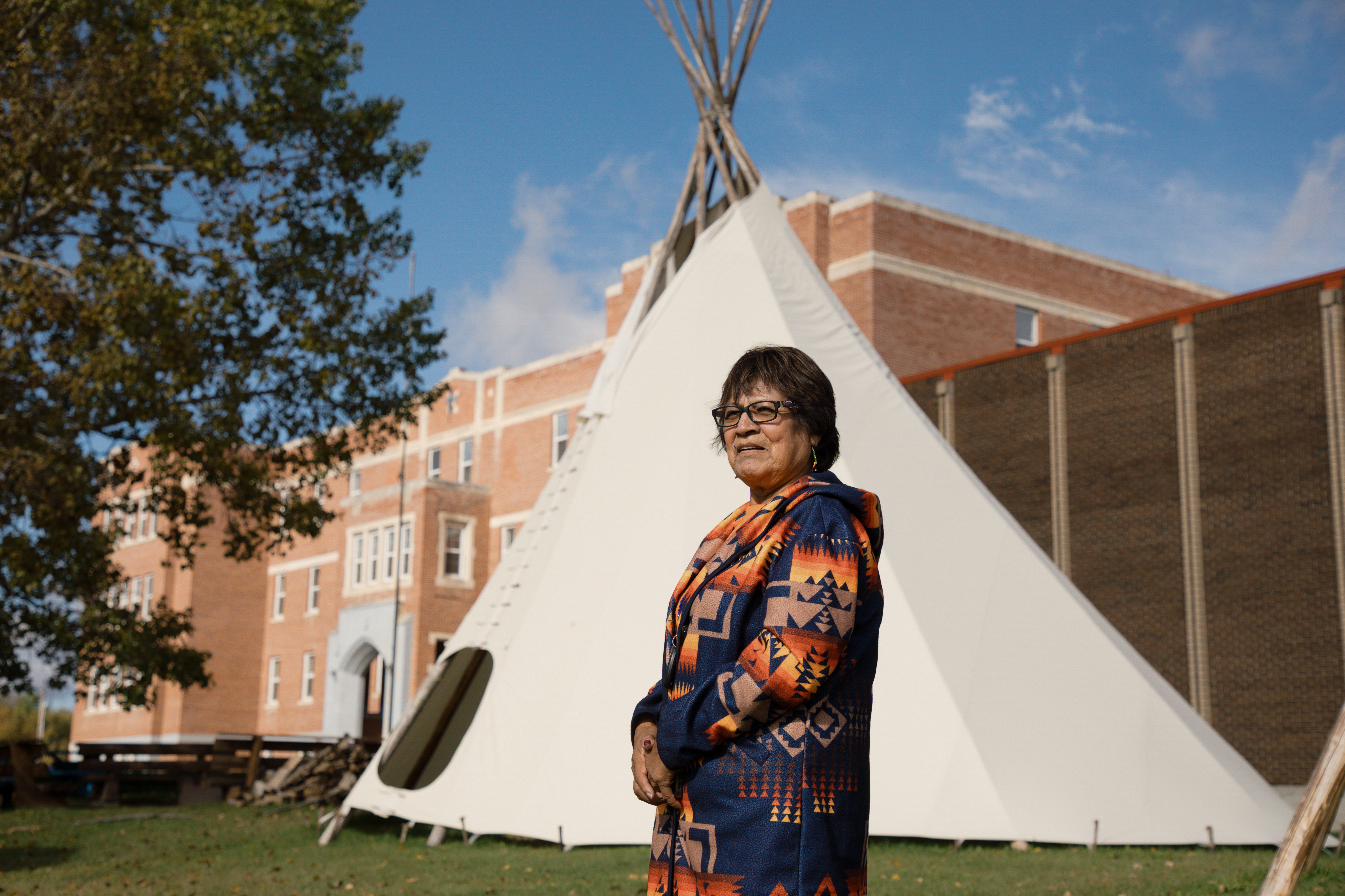 A woman stands in front of a former residential school