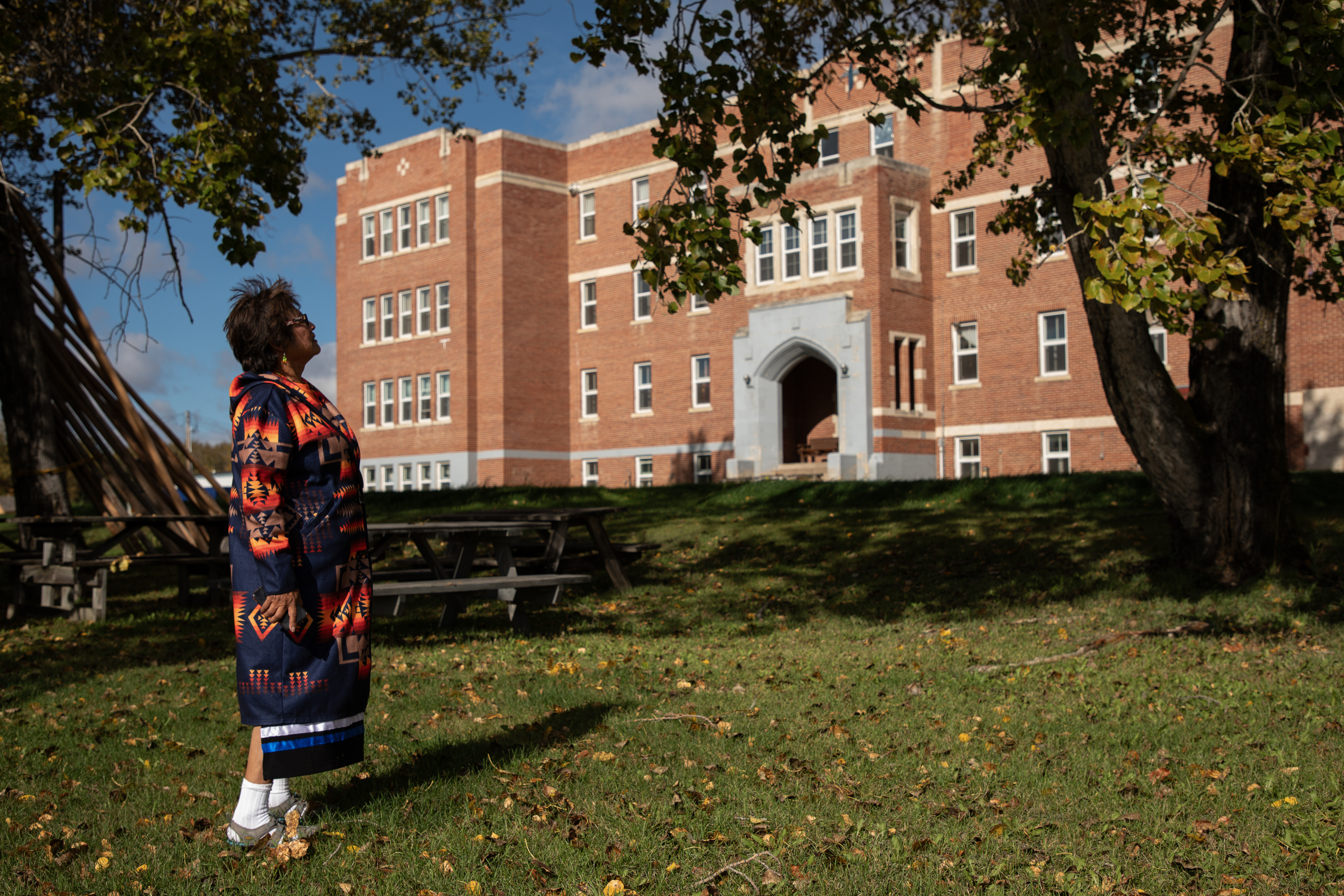 A woman stands on grass looking towatds a large, red stone building