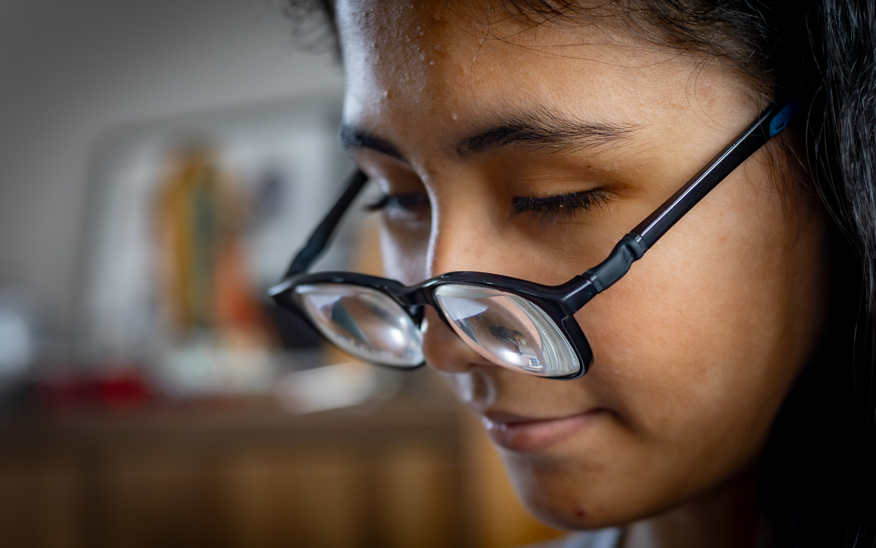 Camila wears glasses and looks down