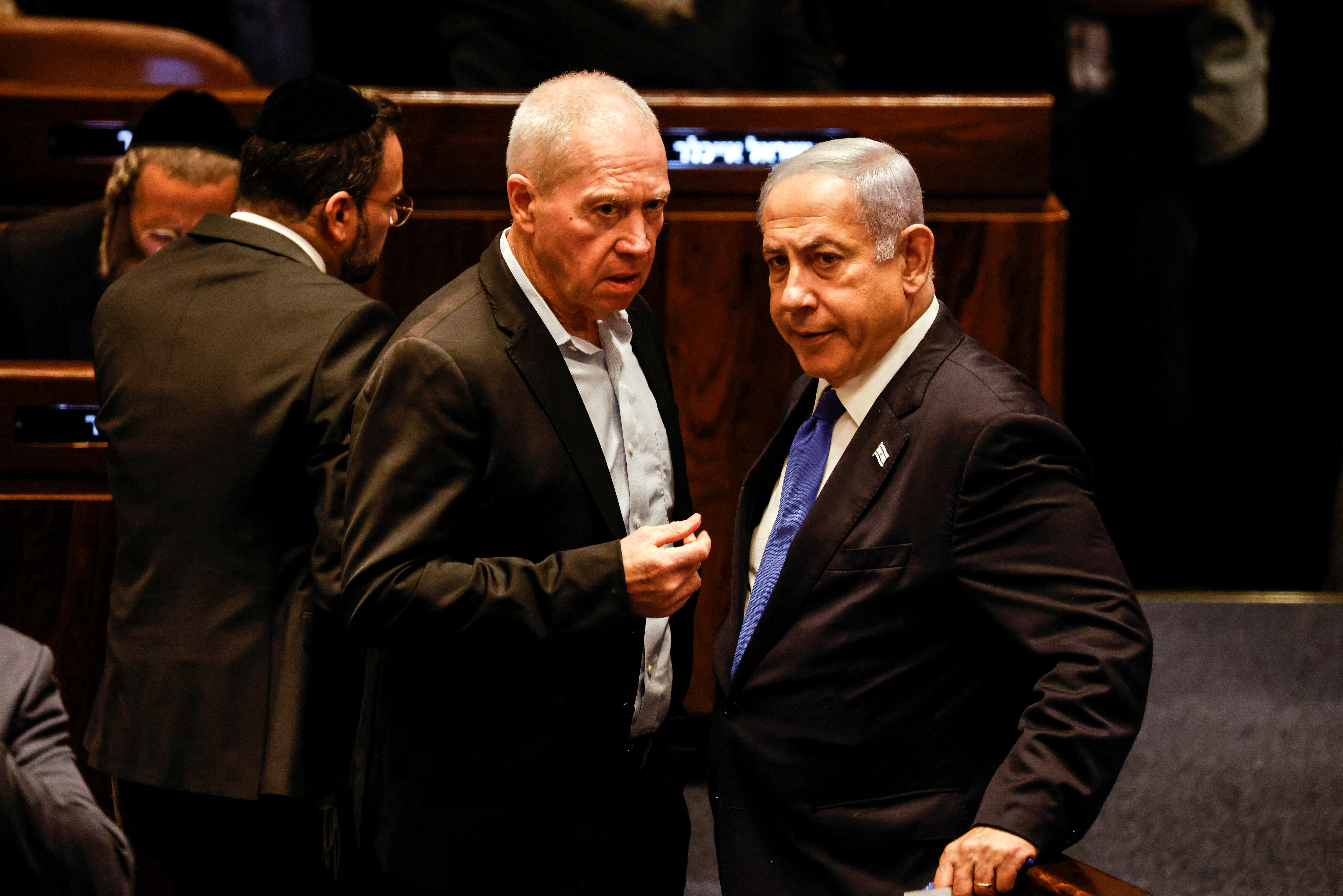 A photo from 24 July 2023 showing then Israeli Defence Minister Yoav Gallant speaking with Prime Minister Benjamin Netanyahu as lawmakers gather at the Knesset to vote on a bill that would limit some Supreme Court power, in Jerusalem.