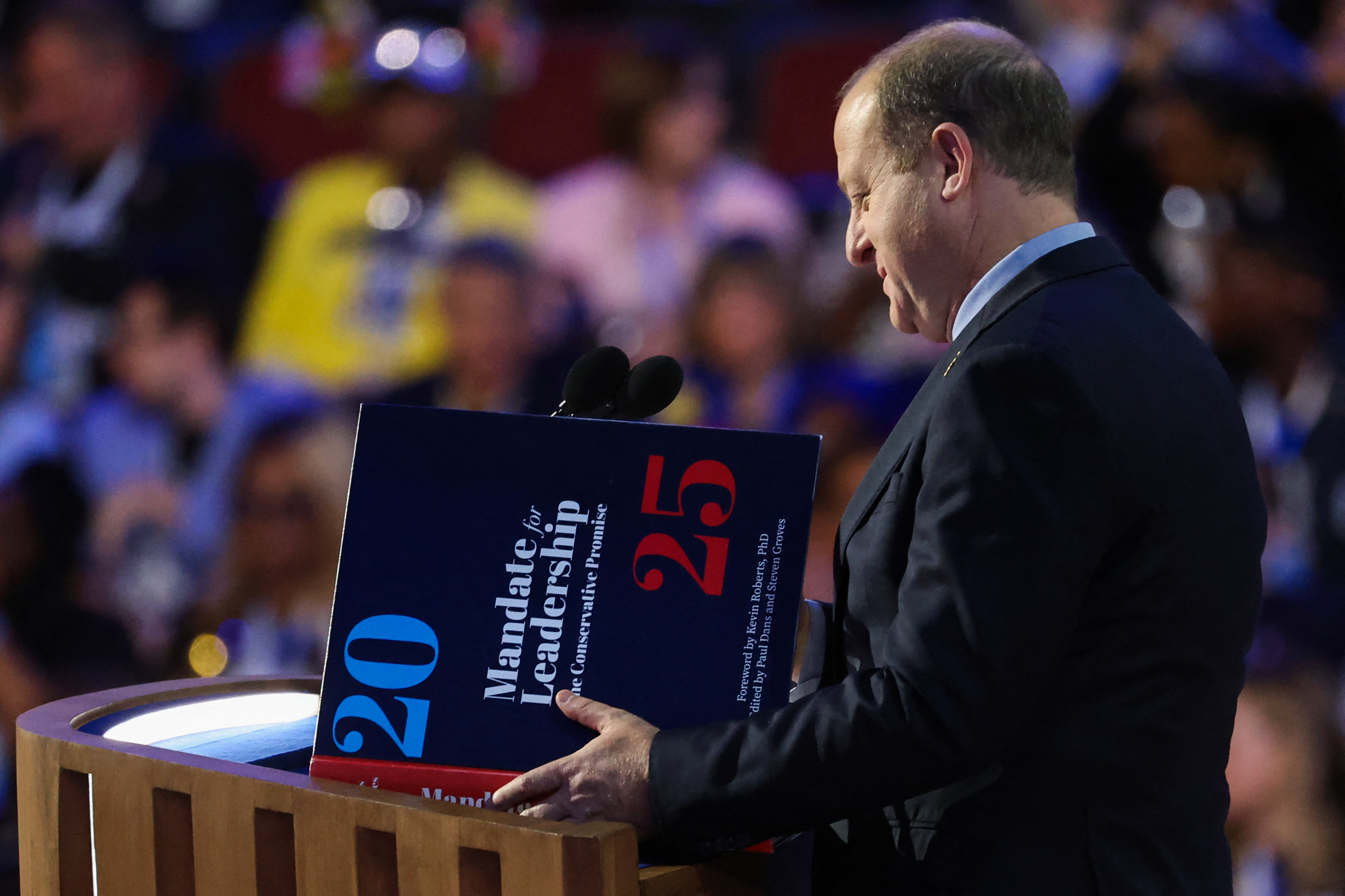 Colorado Governor Jared Polis looks at a book referring to 'Project 2025' on Day 3 of the Democratic National Convention (DNC) in Chicago, Illinois, U.S., August 21, 2024. REUTERS/Brendan Mcdermid