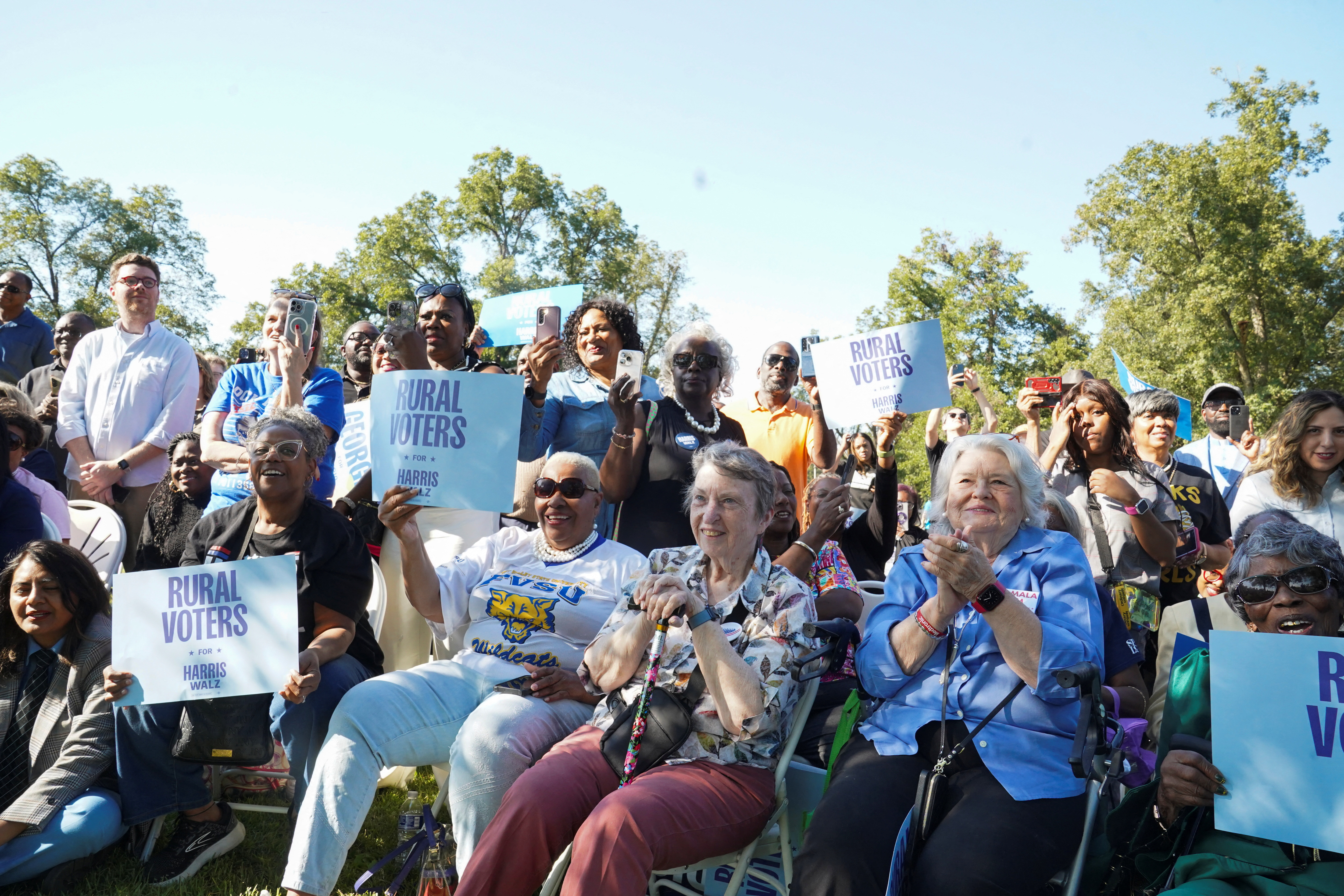 Crowds of voters gather at an outdoor Harris campaign event.
