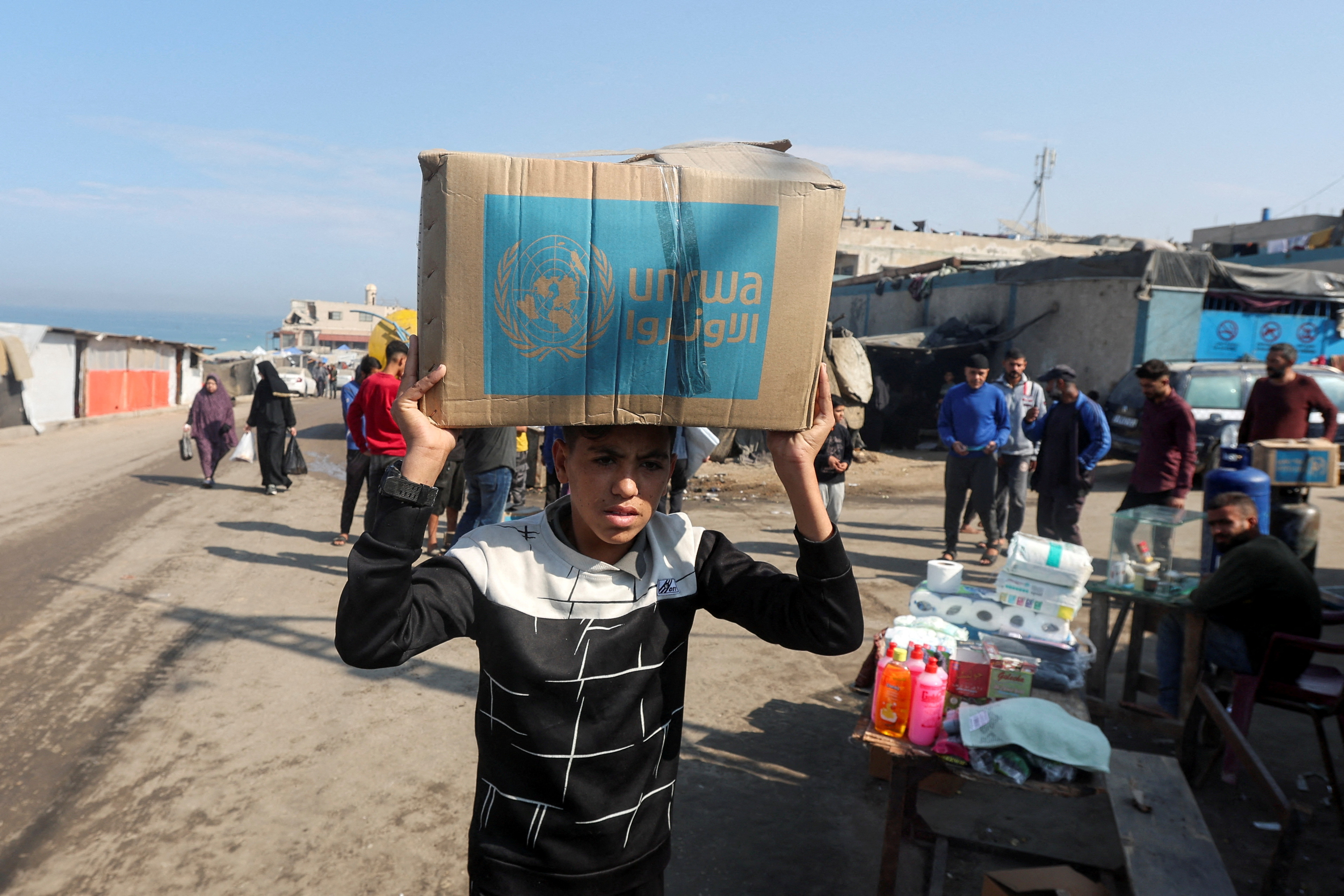 A Palestinian carries an aid box distributed by the United Nations Relief and Works Agency (UNRWA), amid the Israel-Hamas conflict, in Deir Al-Balah, central Gaza Strip, November 4, 2024. [REUTERS/Ramadan Abed TPX IMAGES OF THE DAY]