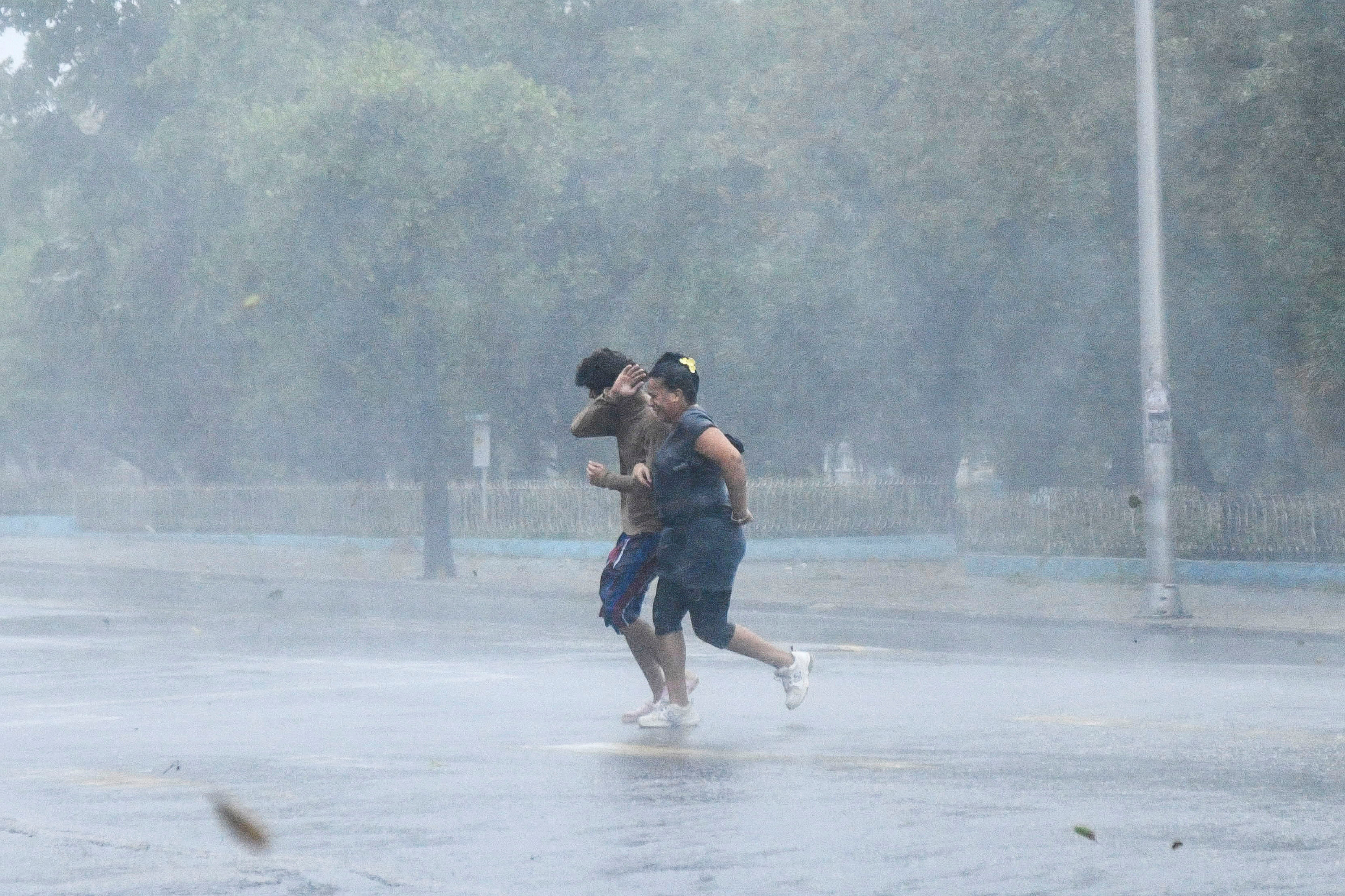 Two people run through torrential rain