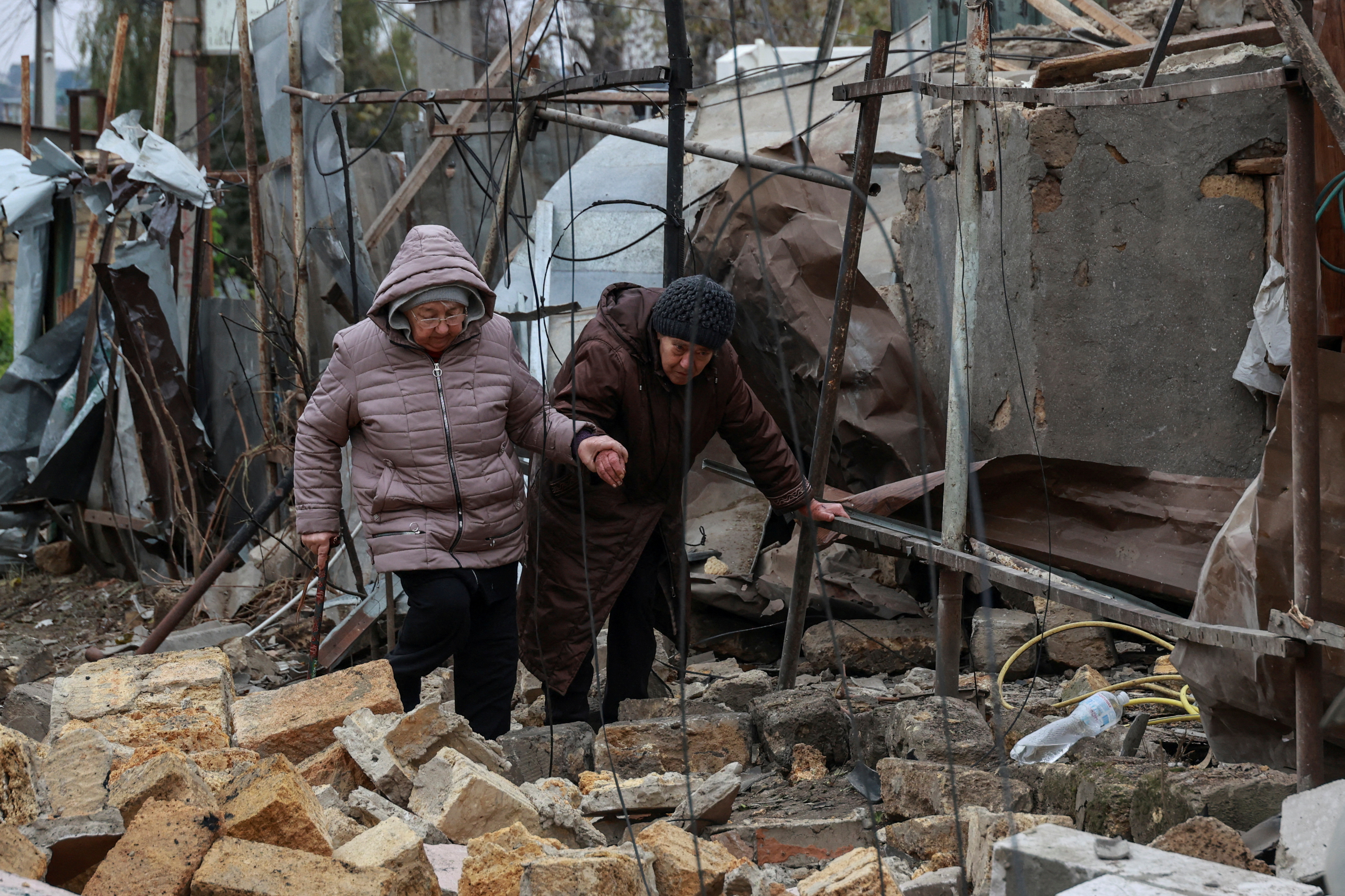 Residents walk through debris at a site of residential area damaged by a Russian drone strike