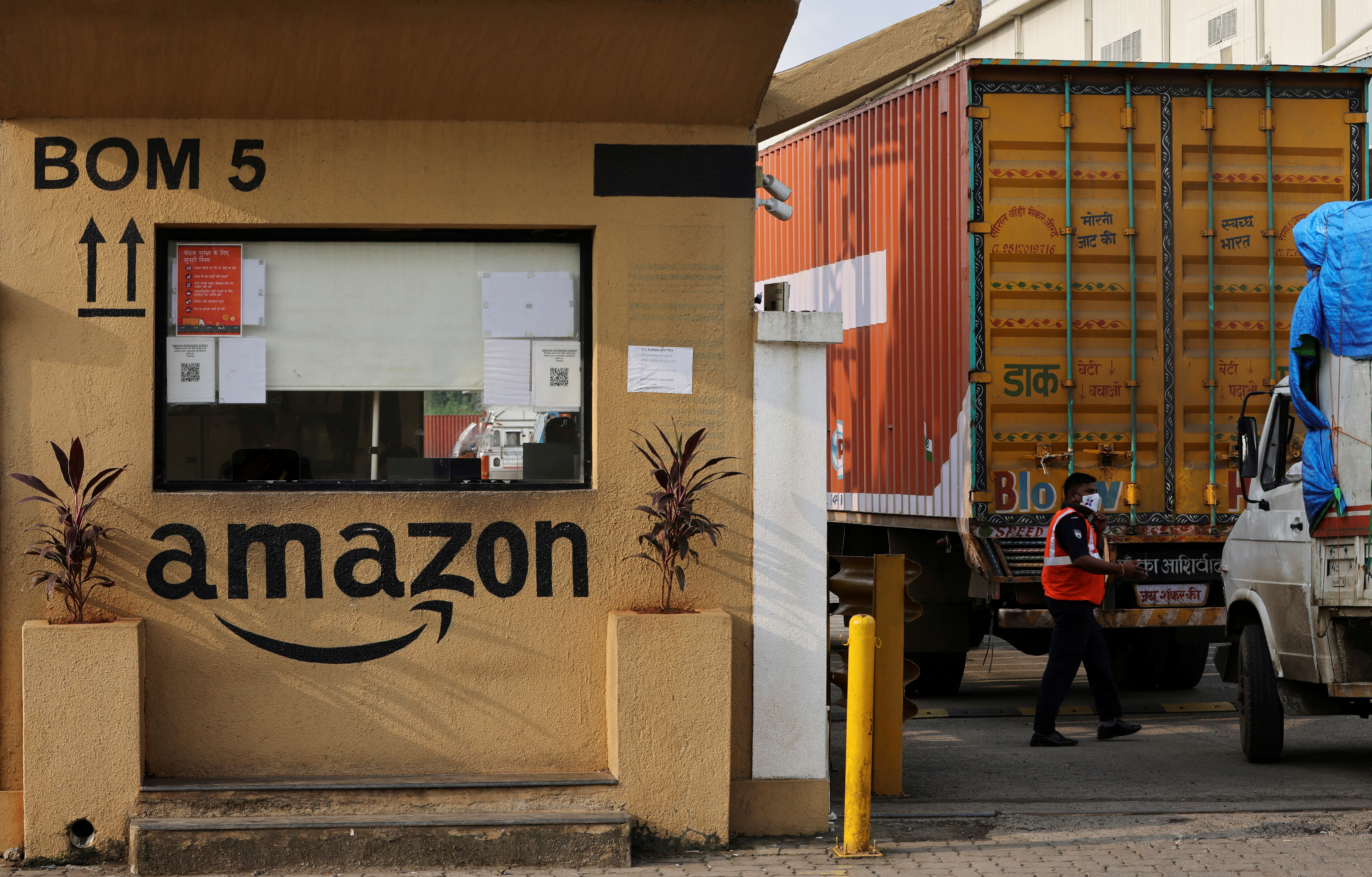 FILE PHOTO: A man inspects trucks before they enter an Amazon storage facility on the outskirts of Mumbai, India, October 1, 2021. Picture taken October 1, 2021. REUTERS/Francis Mascarenhas/File Photo