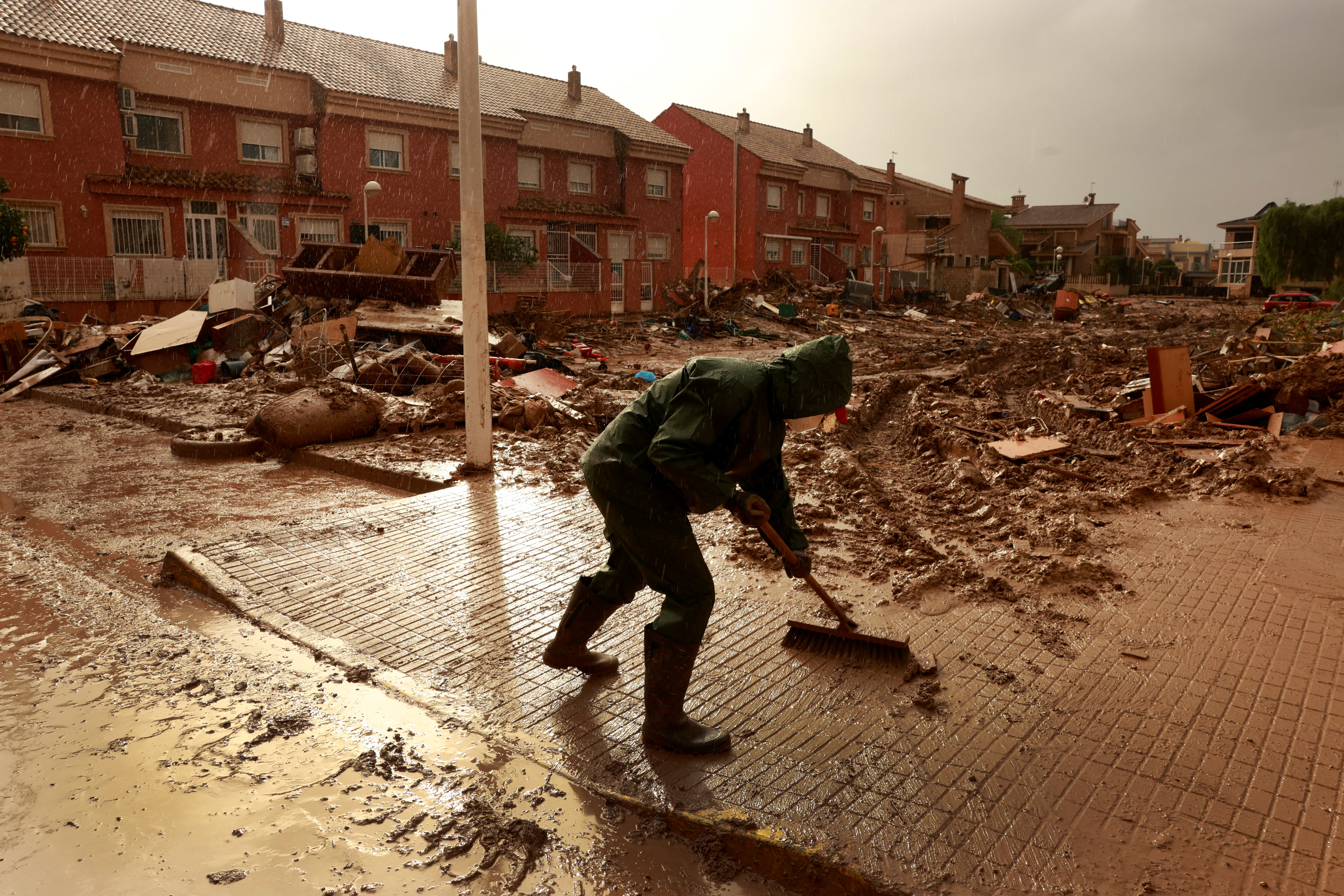 A volunteer cleans muddy water following catastrophic flooding