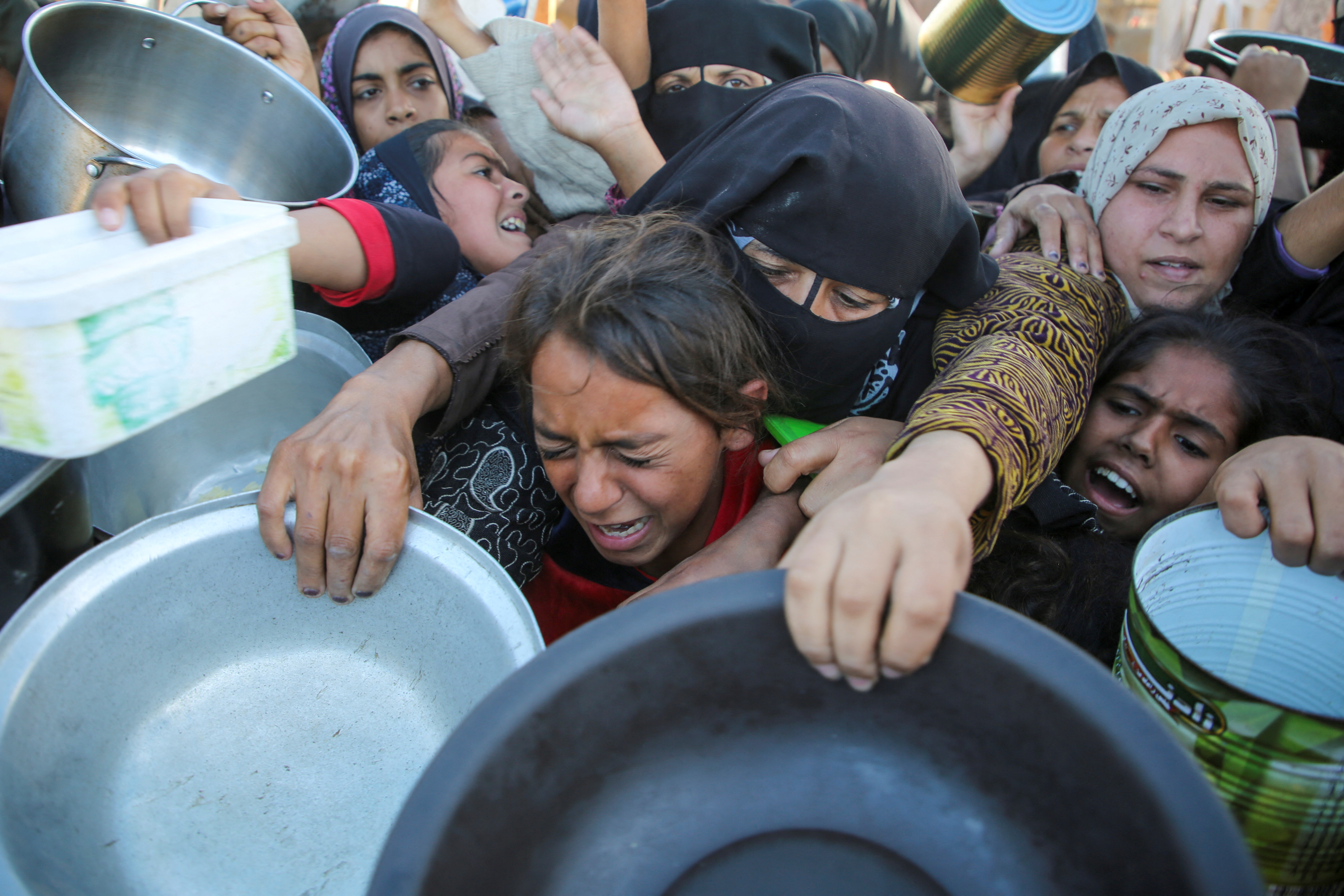 Palestinians gather to receive food cooked by a charity kitchen, amid a hunger crisis, as the Israel-Gaza conflict continues, in Khan Younis in the southern Gaza Strip, November 19, 2024.
