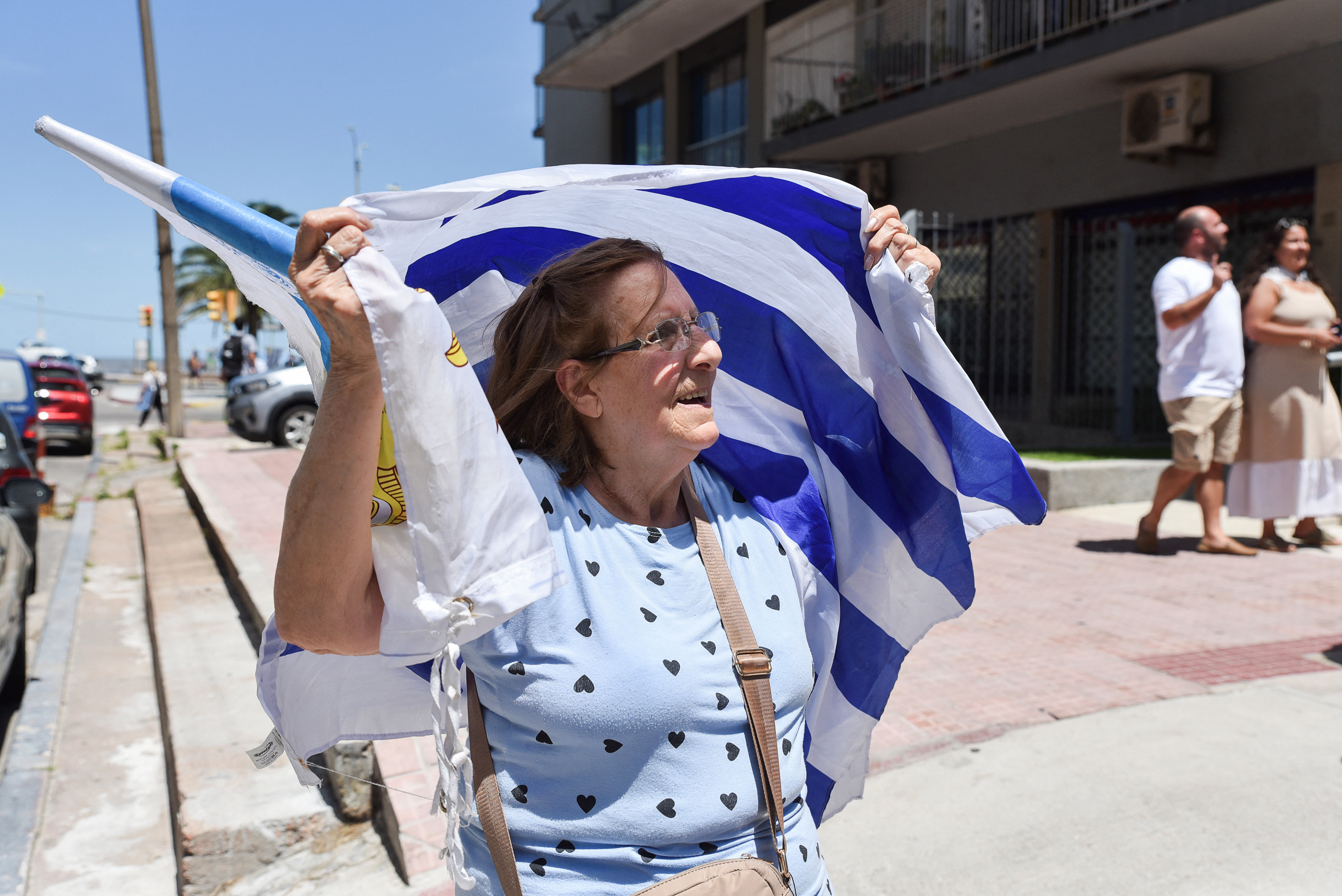A woman holds an Uruguay flag above her head.