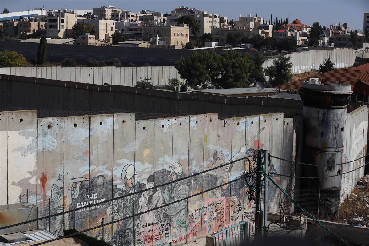 paintings on a concrete wall show a person being blindfolded and led away by soldiers