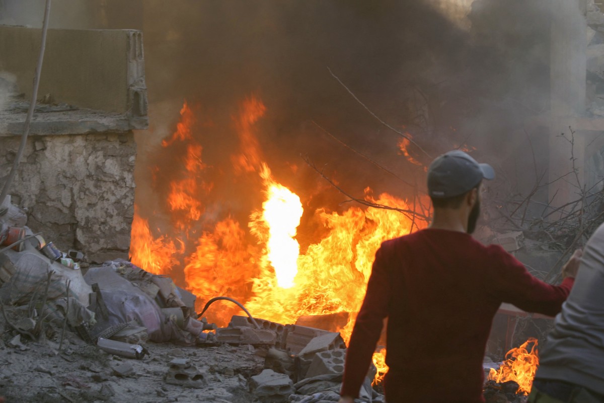 People and rescuers try to put out a fire at the site of an Israeli airstrike