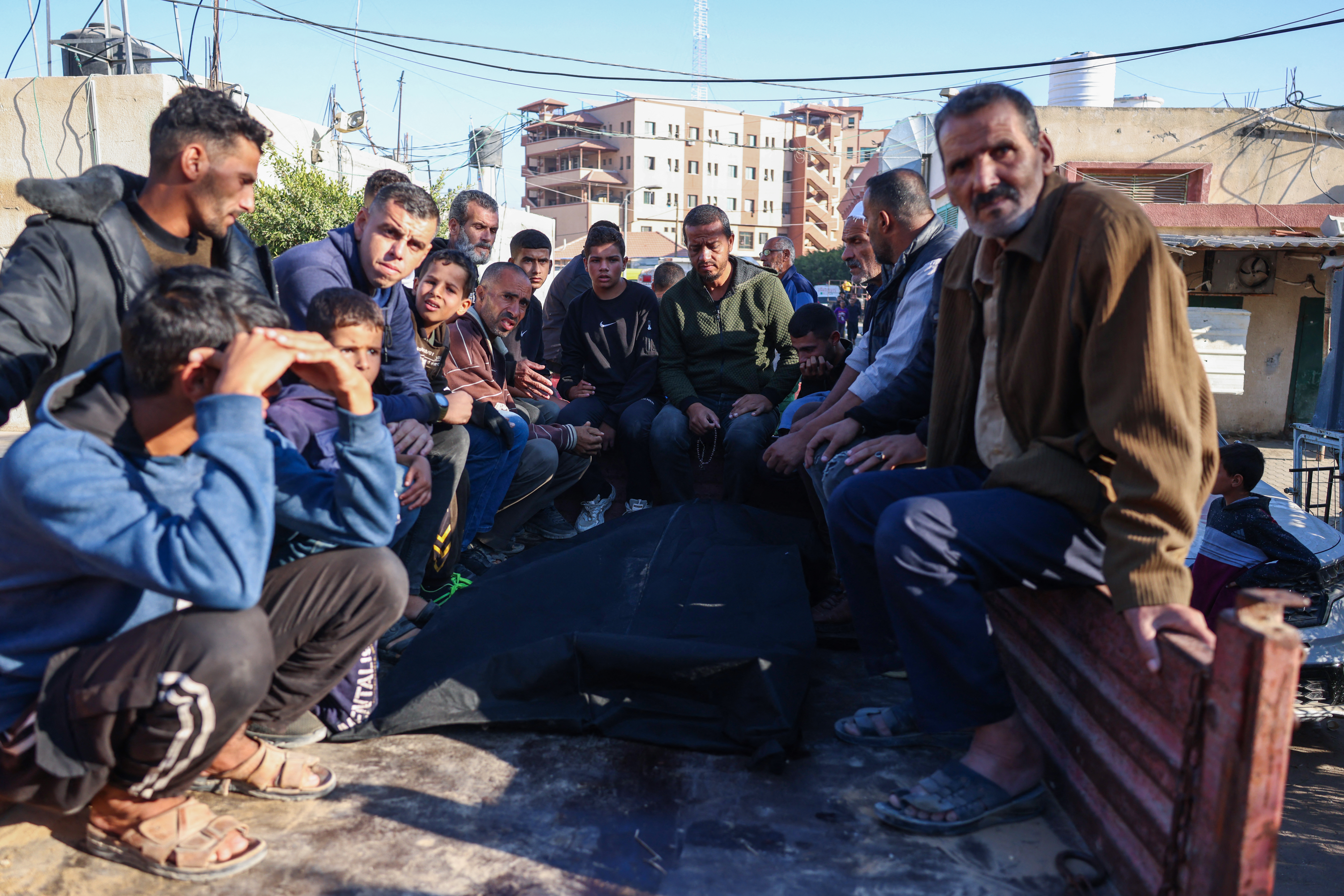 Palestinians sit in the back of a pick-up truck around bodies of relatives killed in overnight Israeli strikes on the al-Mawasi cafeteria in southern Gaza's Khan Yunis