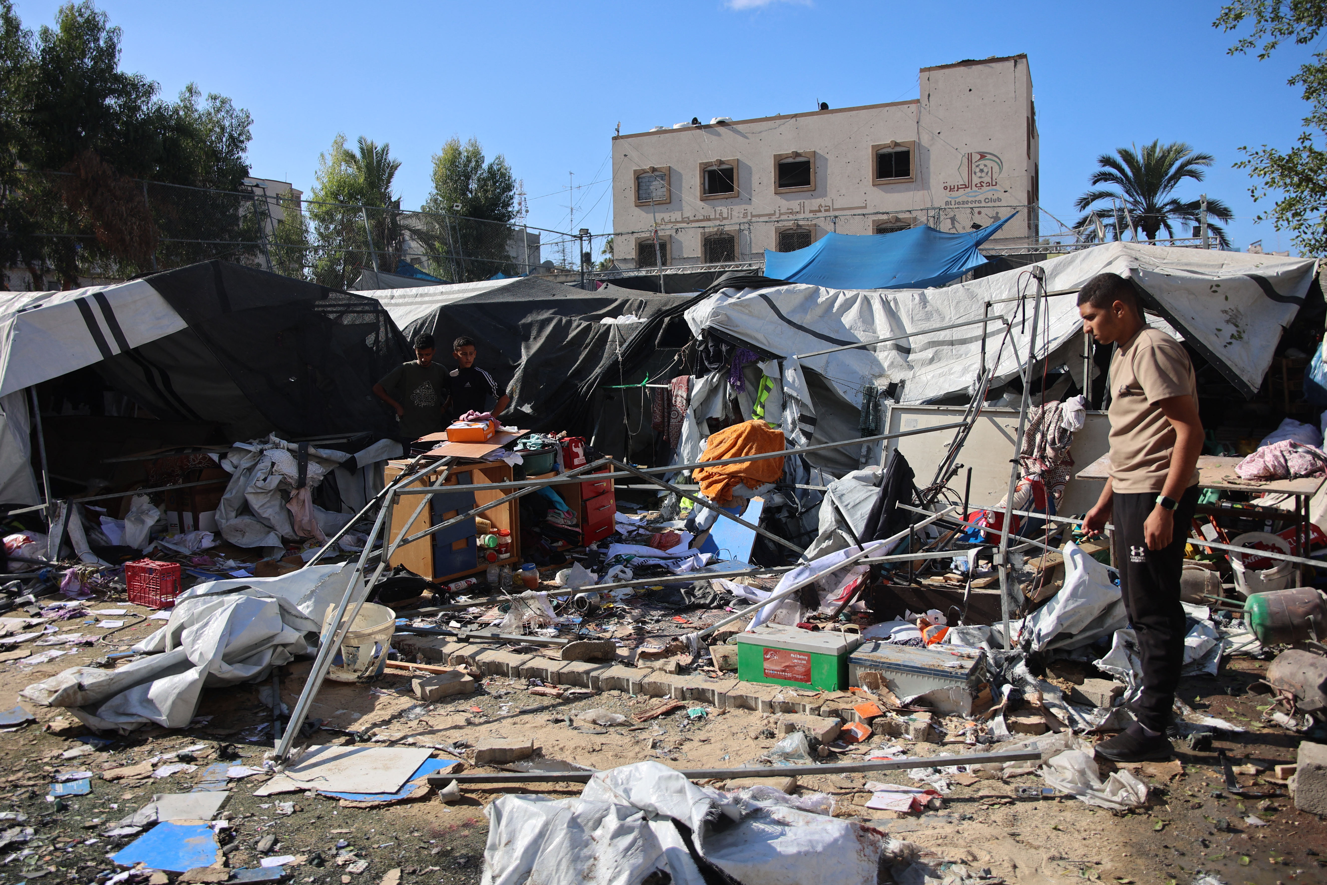 Palestinians inspect the damage following Israeli bombardment which hit a camp for displaced people from other parts of northern Gaza inside the Al-Jazira Sports Club in Gaza City