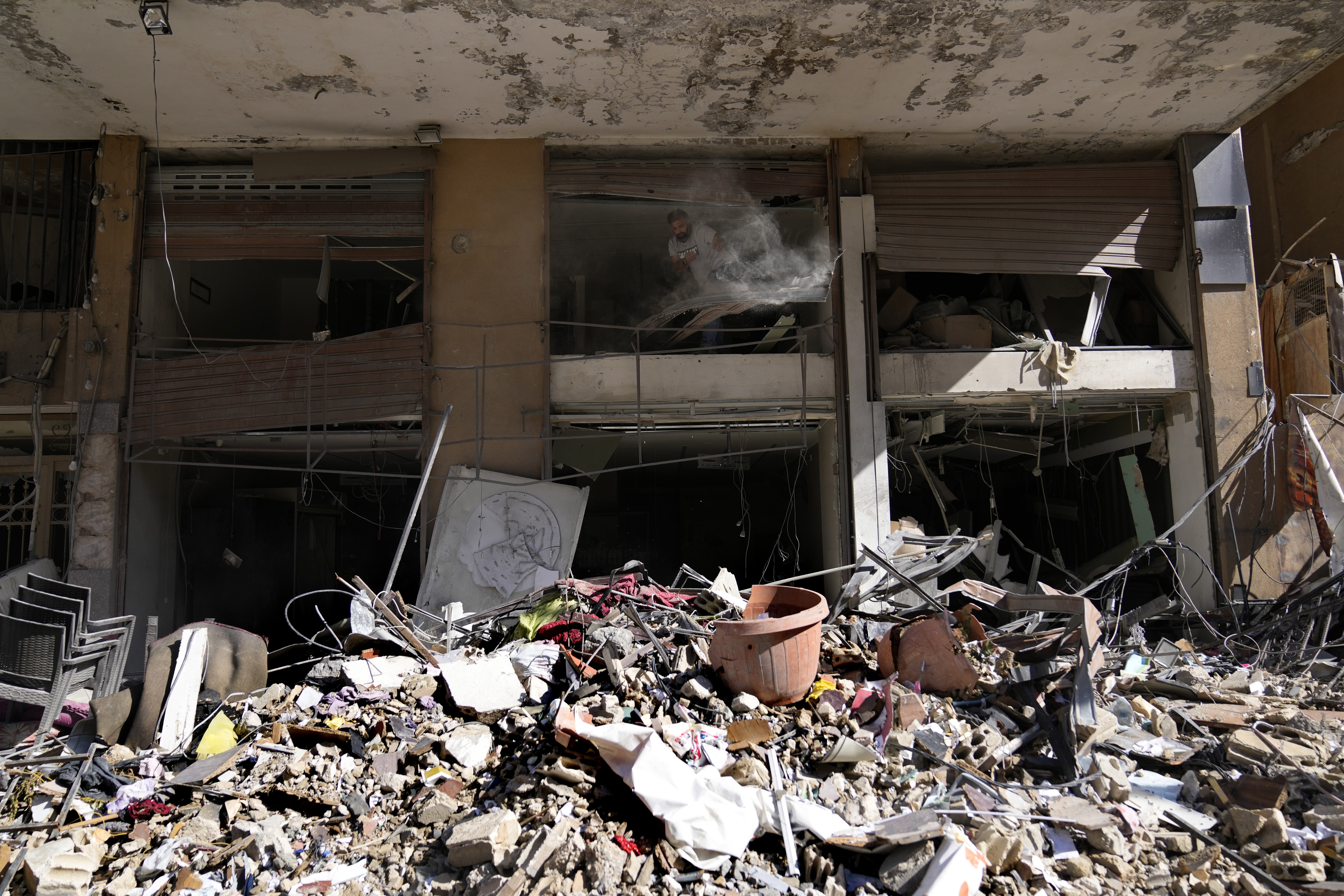 A man removes debris from his damaged shop at a building that was destroyed by an Israeli airstrike in Dahiyeh, in the southern suburb of Beirut