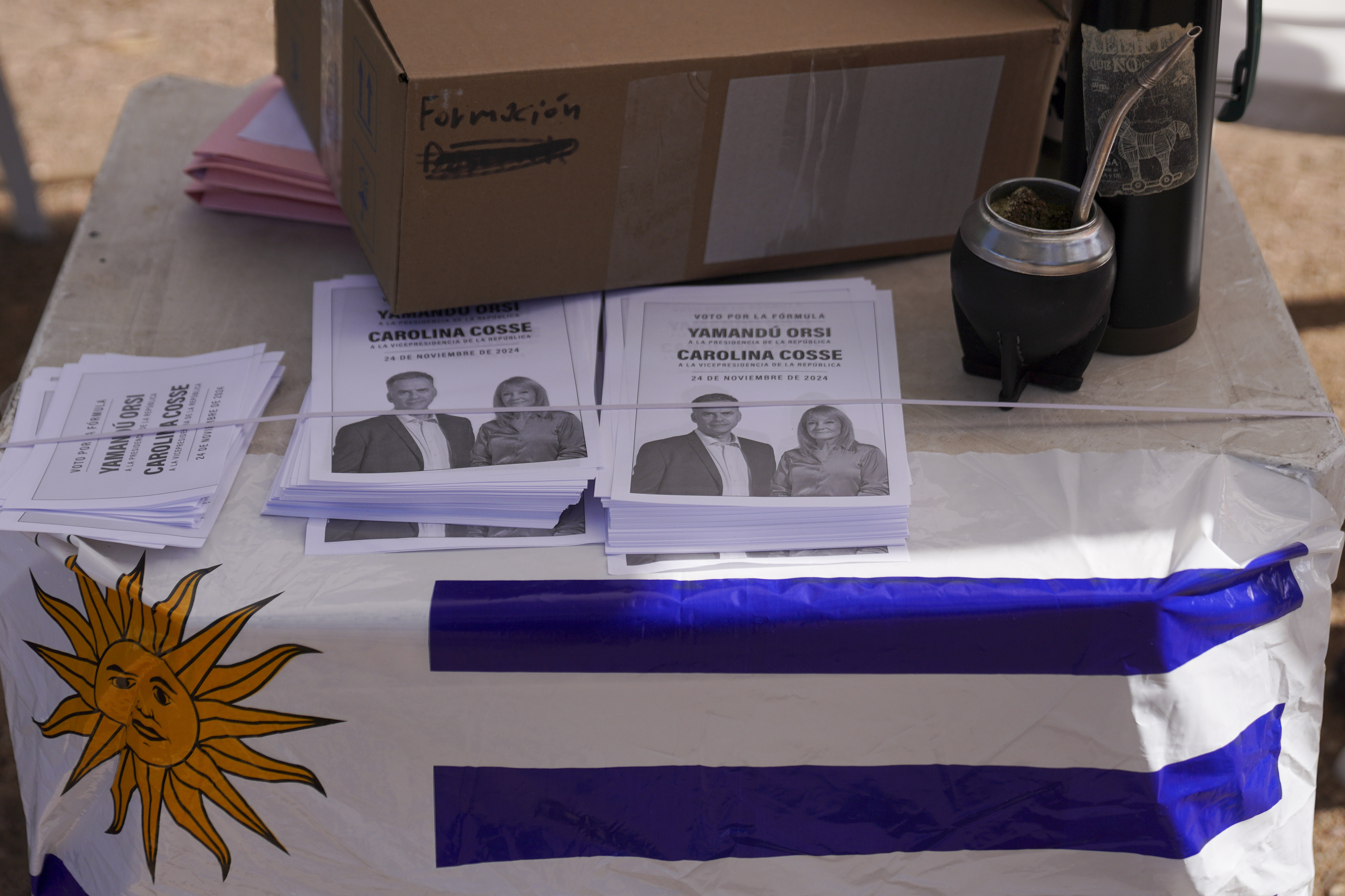 Flyers for the Broad Front coalition sit on a table above an Uruguay flag.