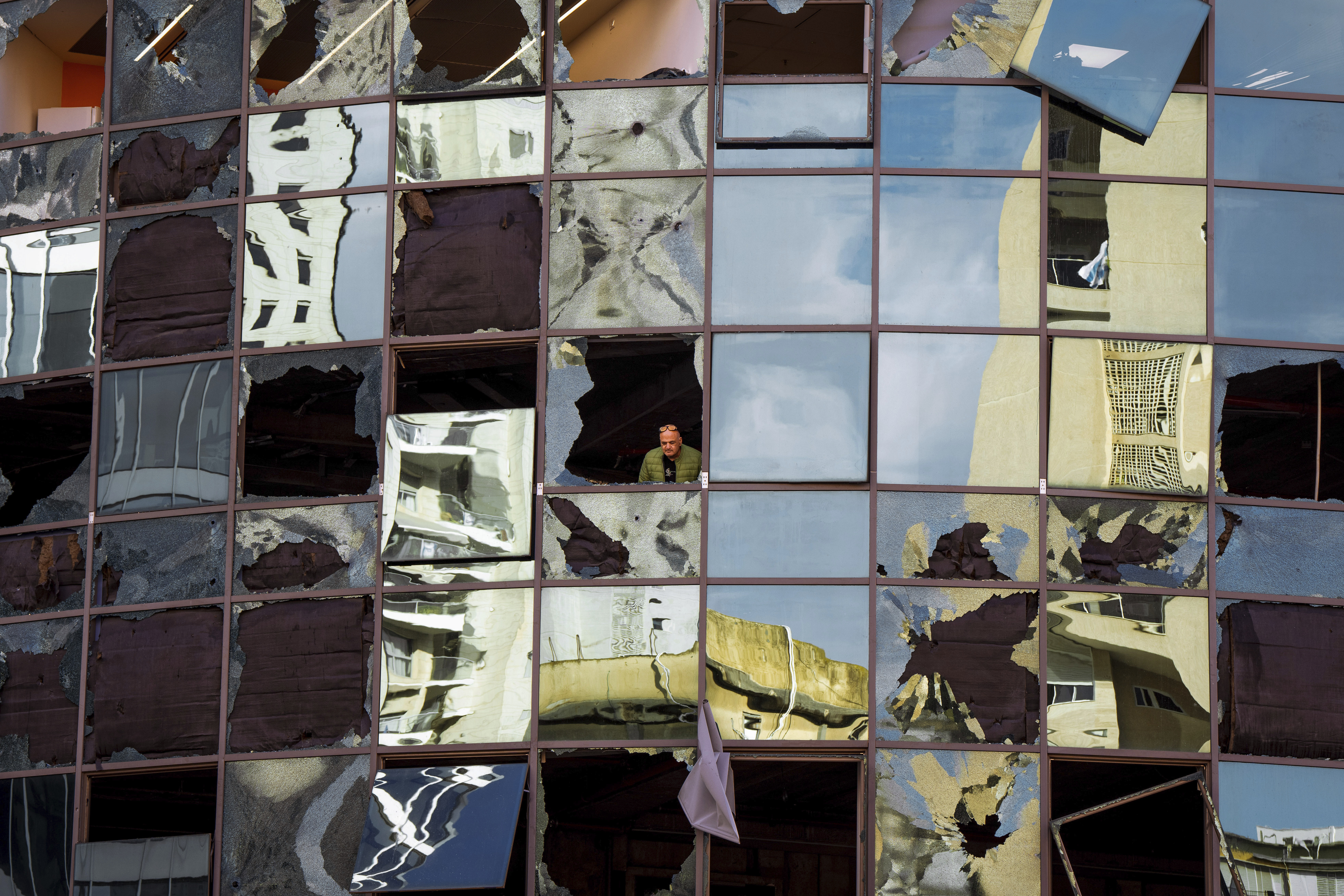 A man looks from a damaged building a day after it was hit by a rocket fired from Lebanon, in Ramat Gan