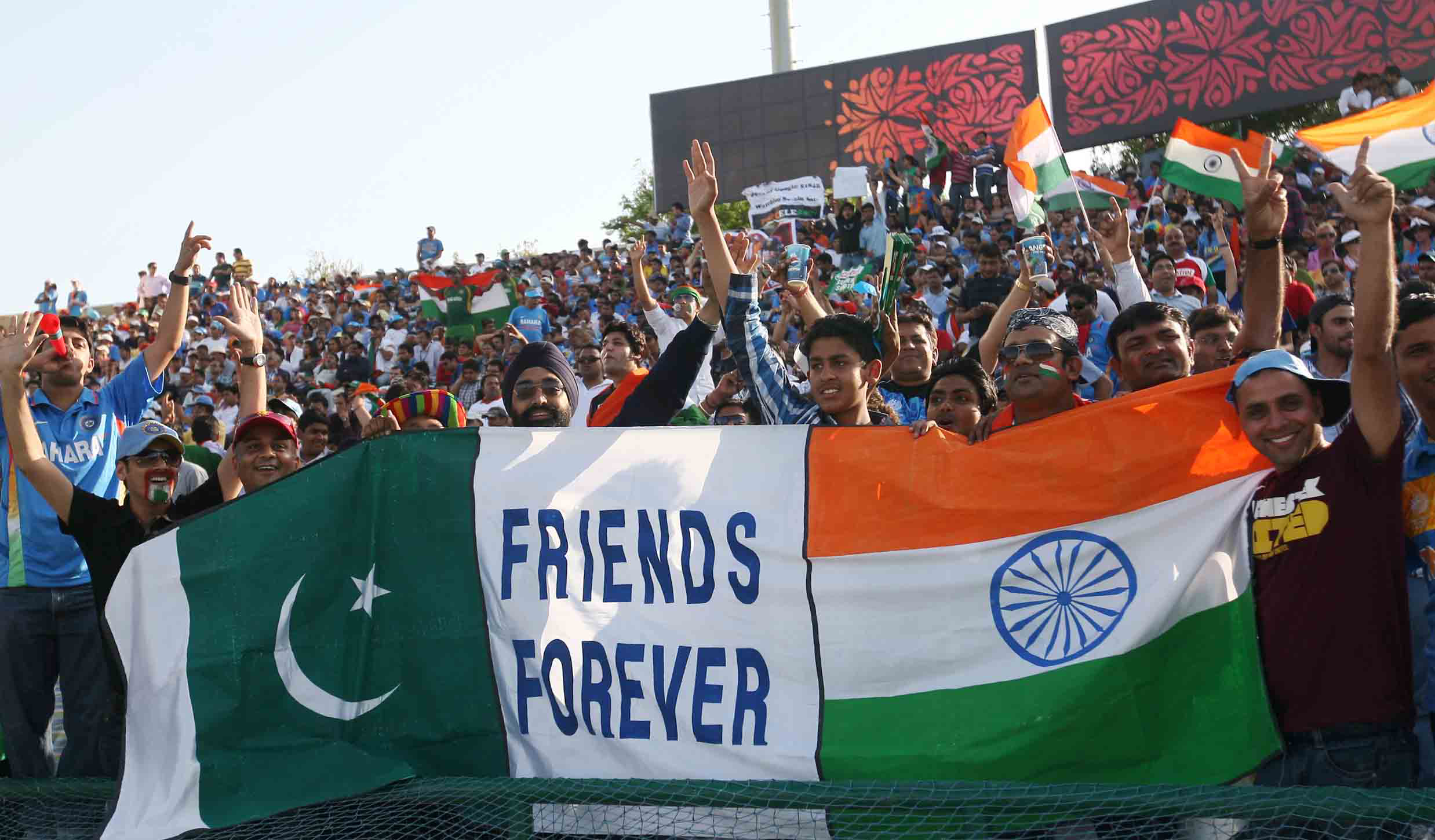 Cricket fans hold India and Pakistan flags.