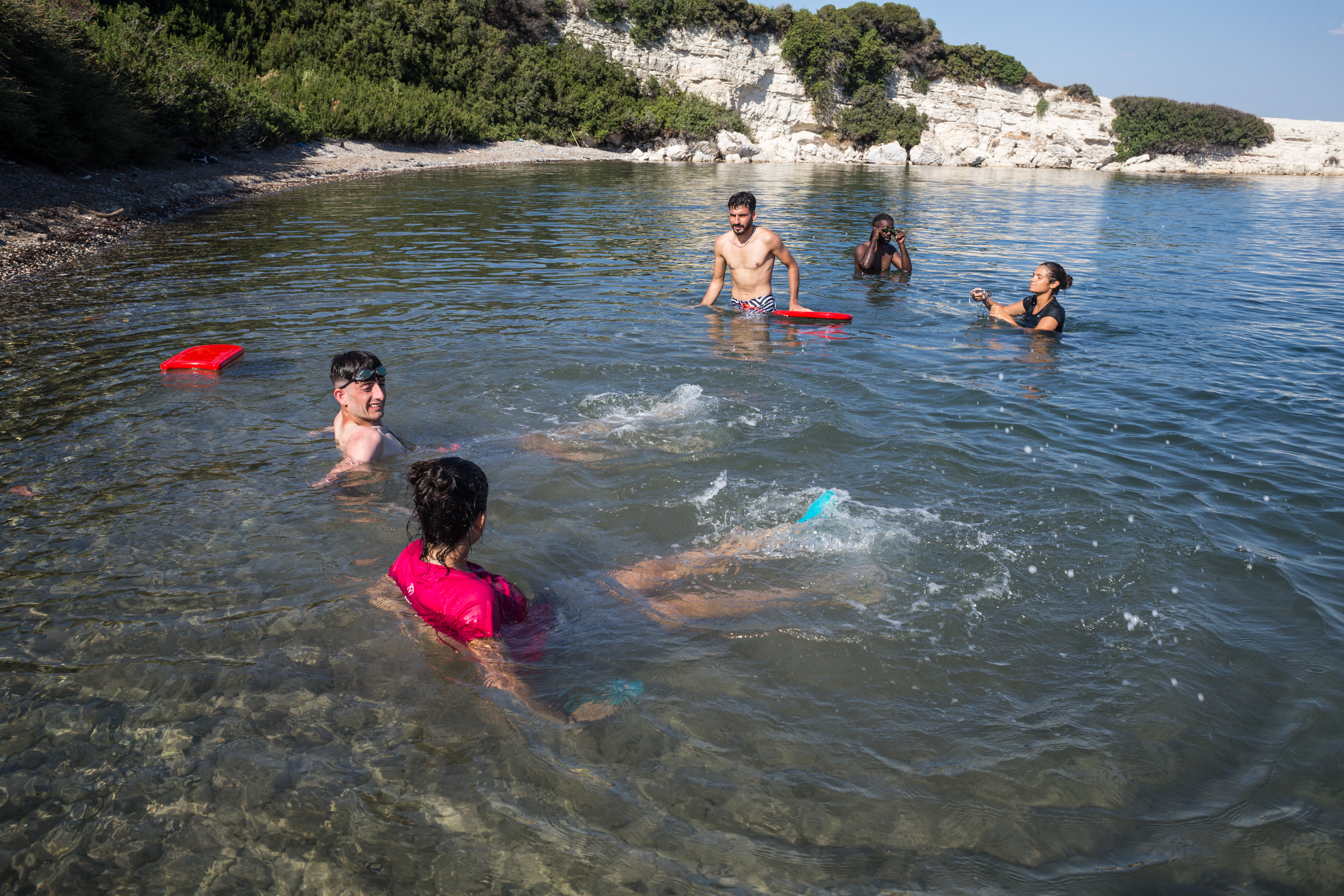 Sarah Emma Balamurugan Sevilla (bottom left) teaches a swimmer student how to kick their feet in the water. [Giacomo Sini/Al Jazeera]