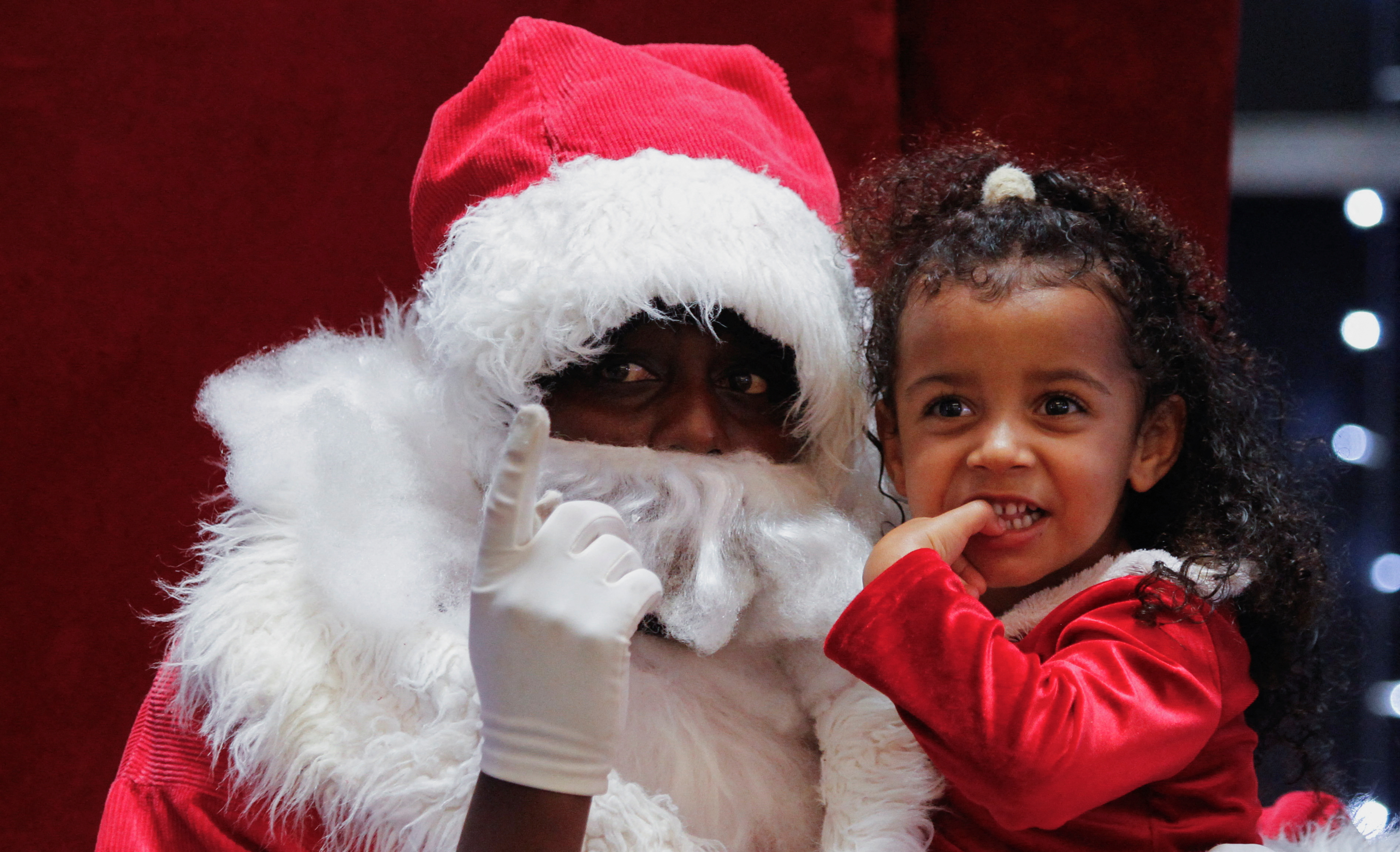 A Santa Claus in Nairobi sits with a little girl