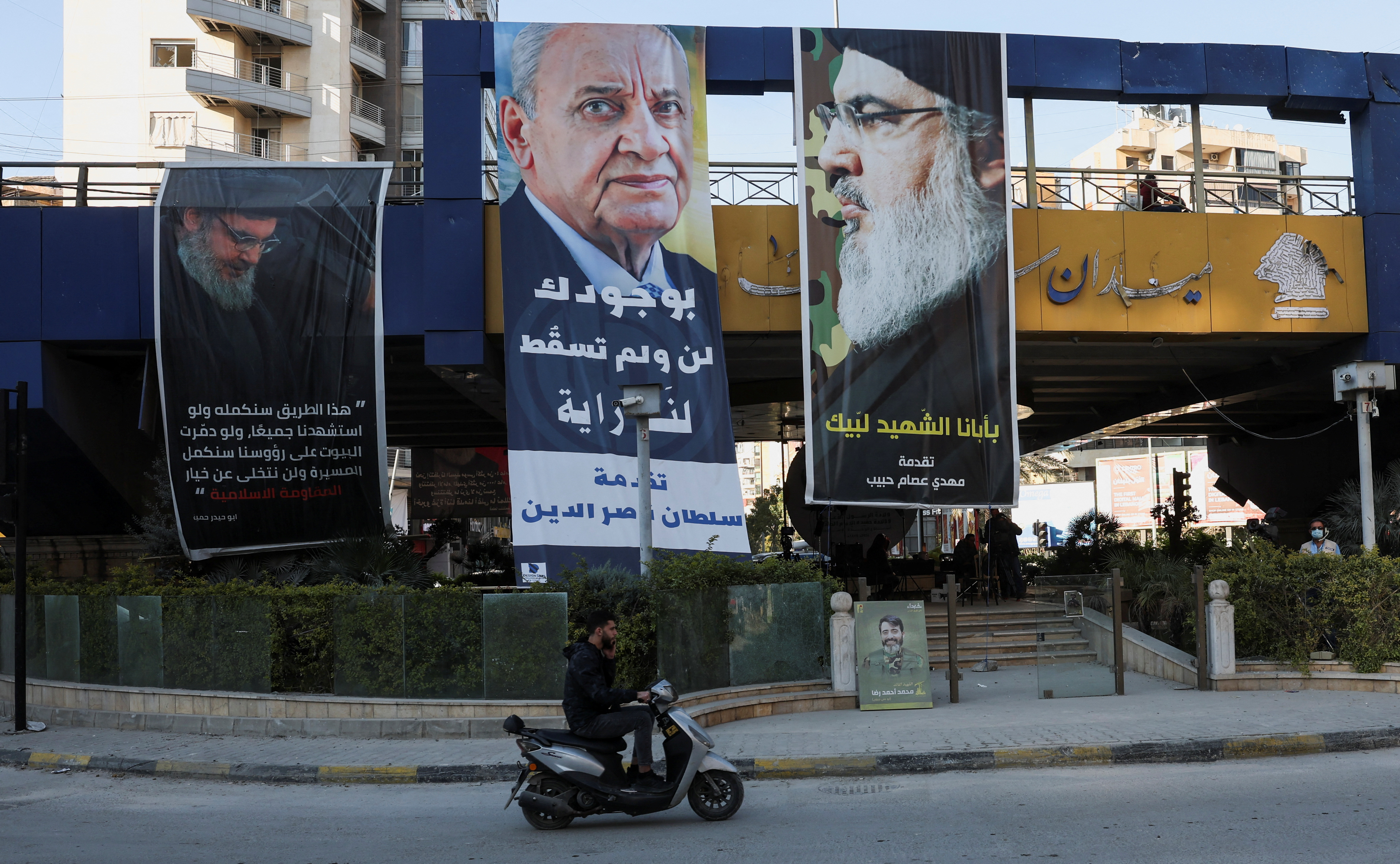 A person rides a motorbike past a poster depicting Lebanese Parliament Speaker Nabih Berri and late Hezbollah leader Hassan Nasrallah in Beirut's southern suburbs, December 2, 2024. [Mohamed Azakir/Reuters]