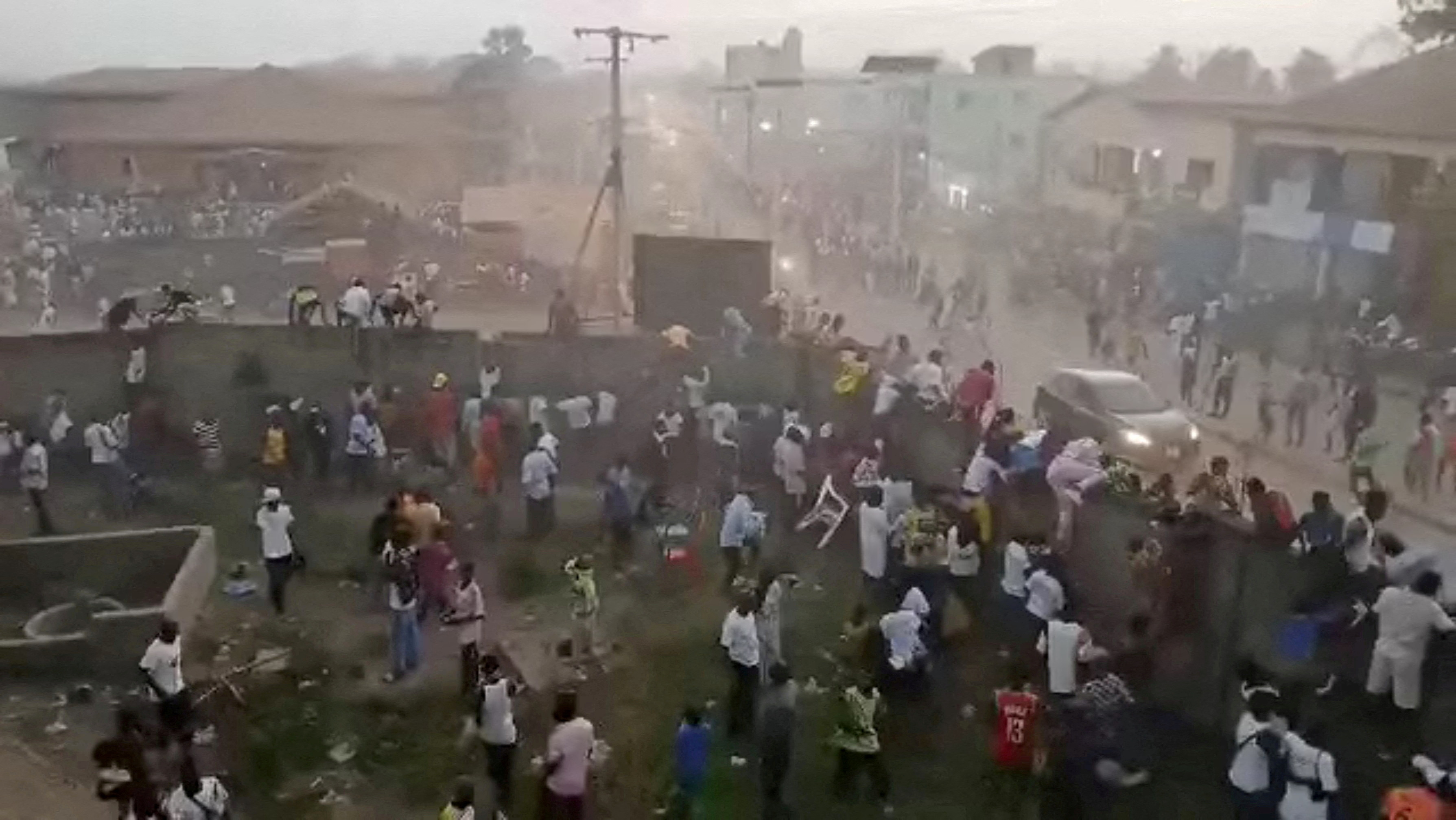 People scramble in Nzerekore, Guinea, where local officials said a deadly crush ensued at a stadium following fan clashes during a soccer match