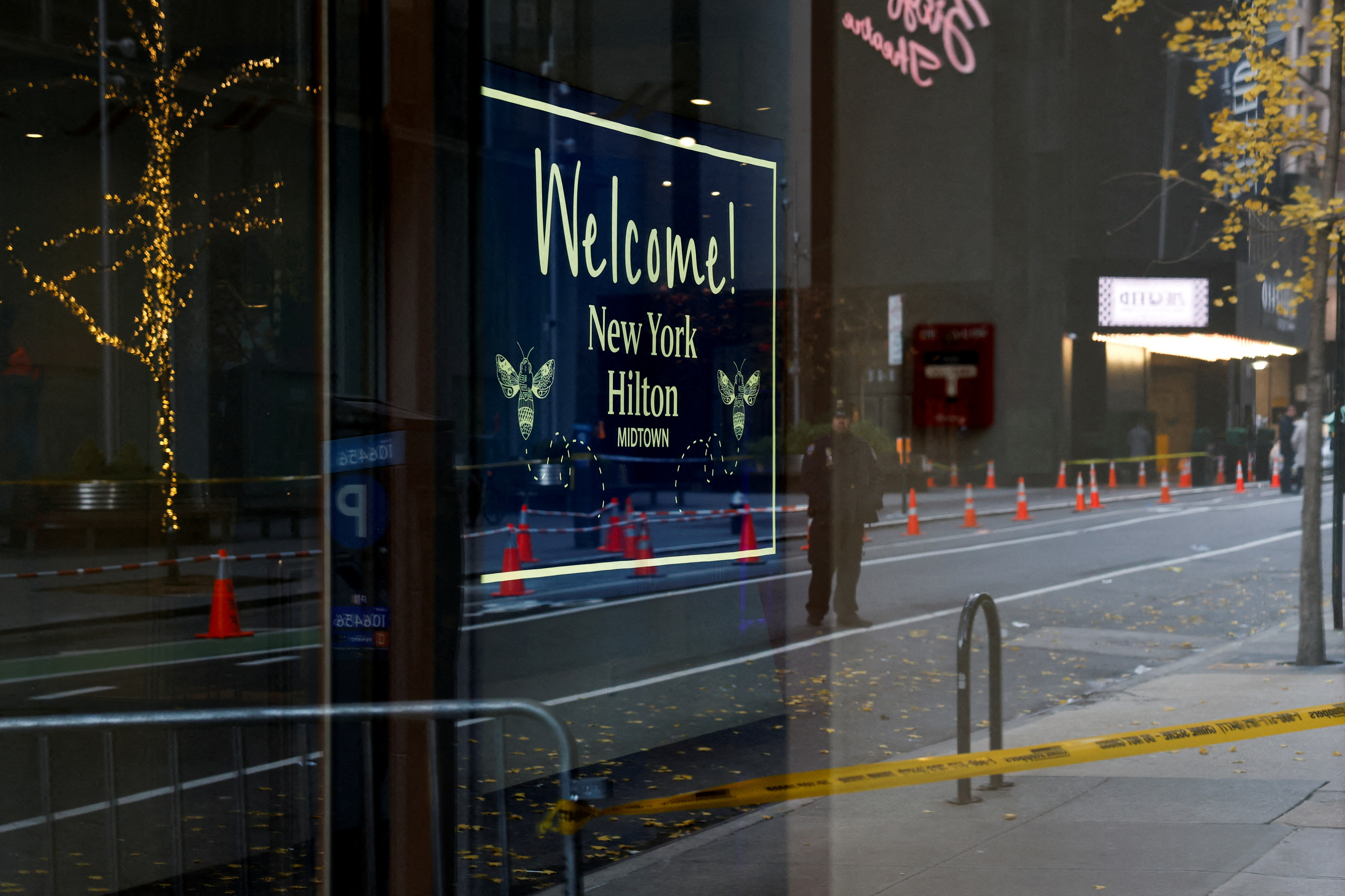 A police officer is reflected in a hotel window near the scene where the CEO of UnitedHealthcare Brian Thompson was reportedly shot and killed in Midtown Manhattan, in New York City