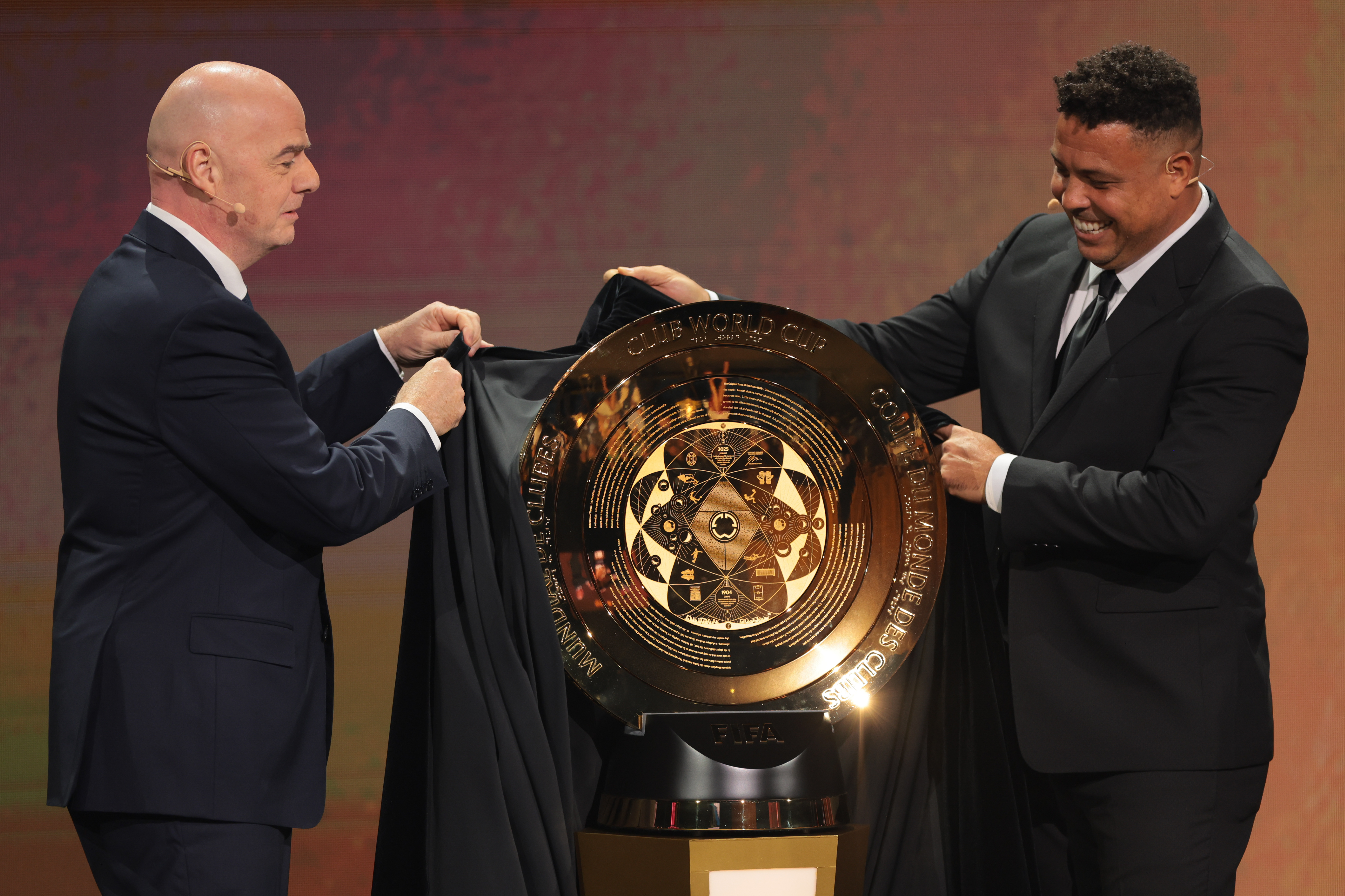 Dec 5, 2024; Miami, FL, USA; FIFA president Gianni Infantino (left) and Brazilian former soccer player Ronaldo Nazario unveil the FIFA Club World Cup trophy during the Club Word Cup draw at Telemundo Studios. Mandatory Credit: Sam Navarro-Imagn Images