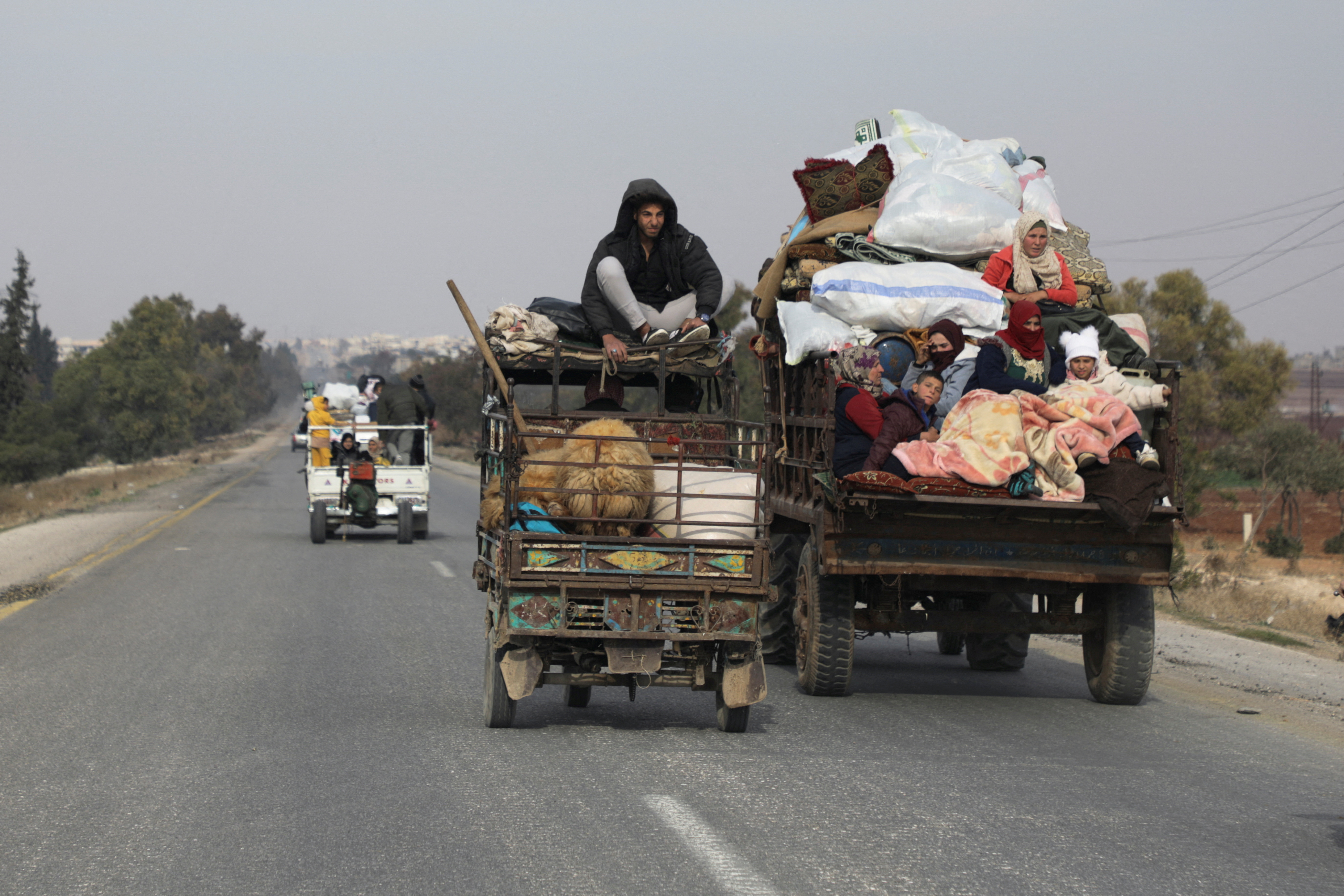 People ride on a vehicle with their belongings in Hama after opposition forces took control of the city in Syria