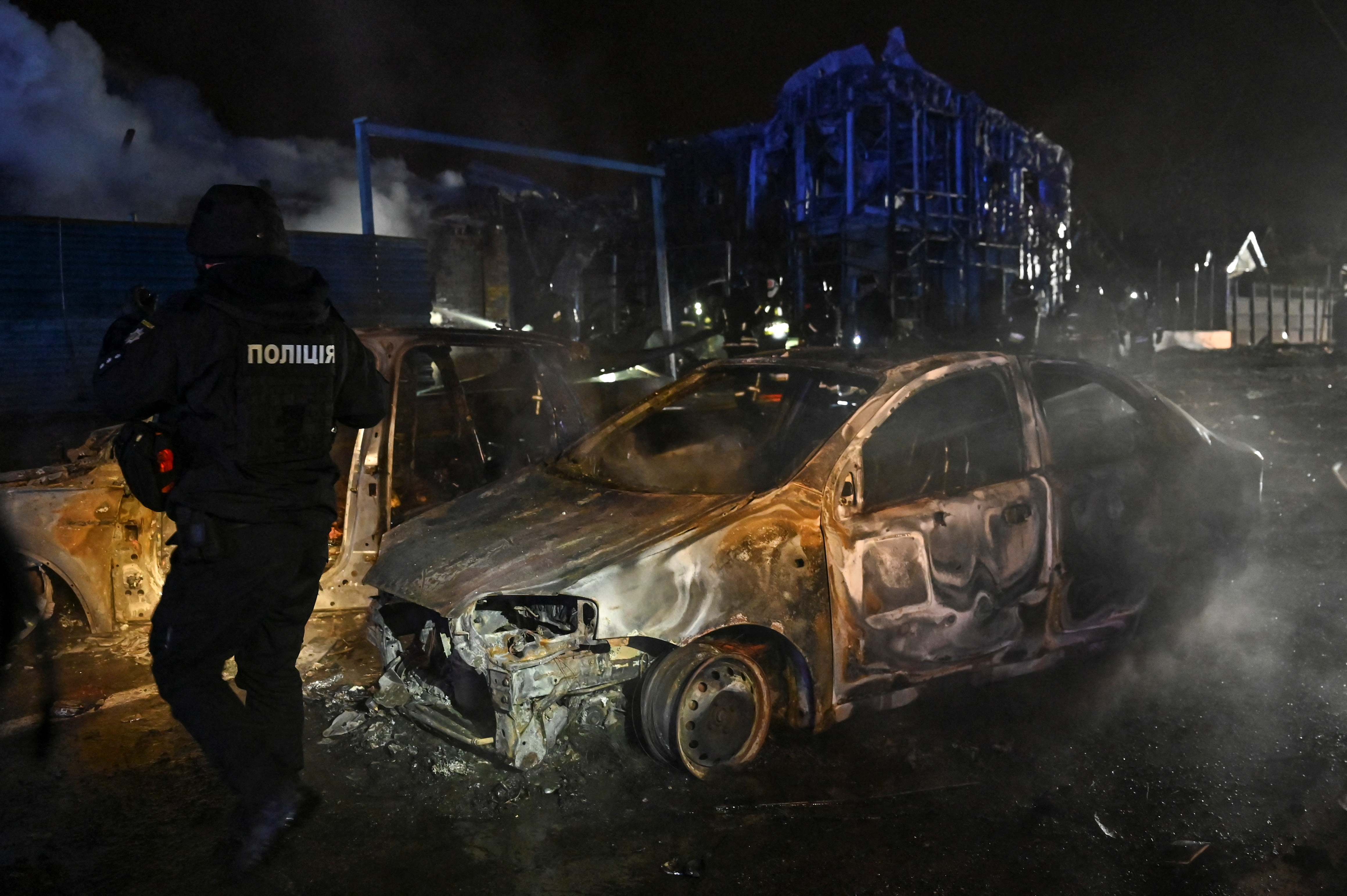 A police officer inspects destroyed cars at the site of a Russian attack in Ukraine
