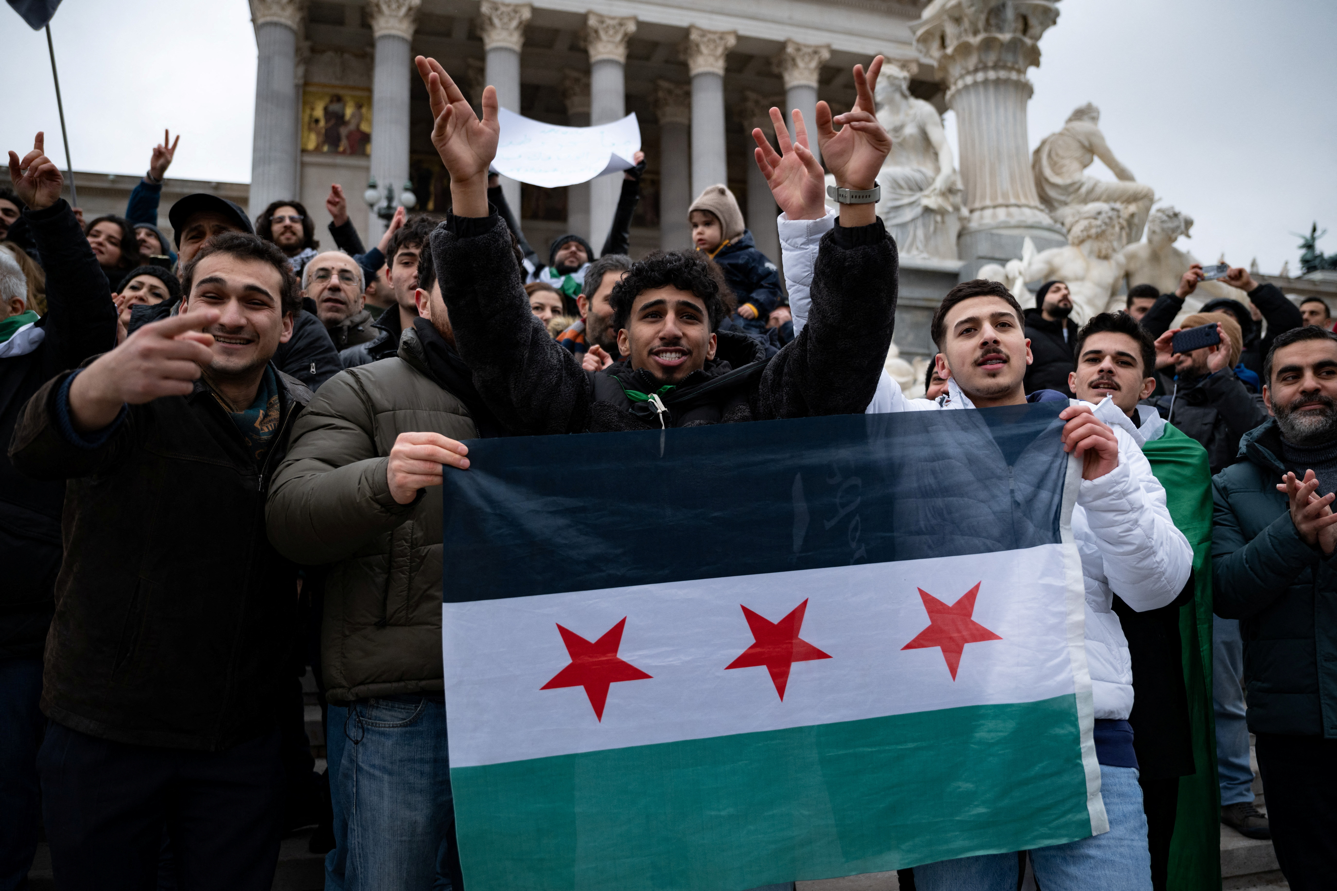 People react, as they gather in front of Parliament, after Syrian rebels announced that they have ousted President Bashar al-Assad, in Vienna,